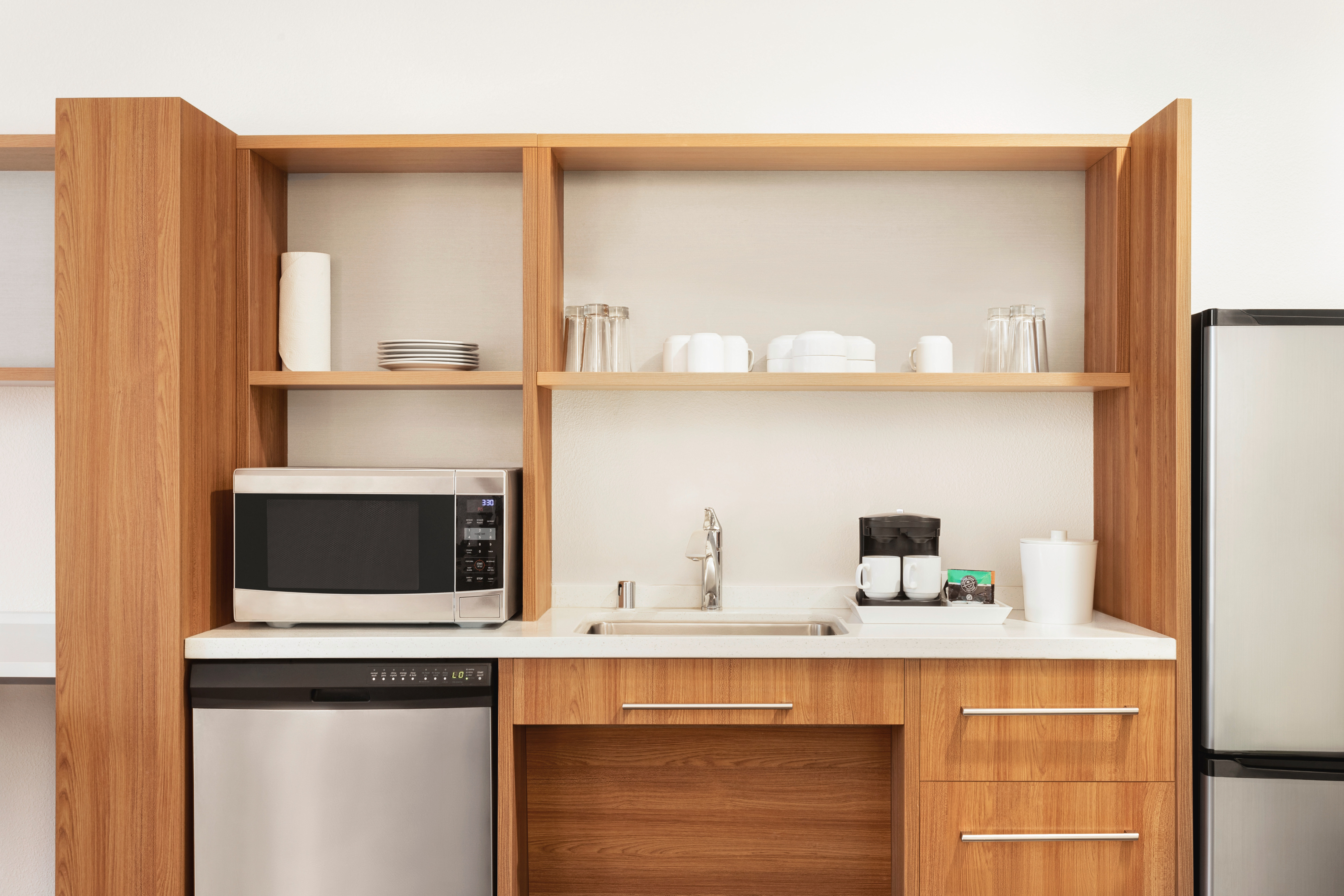 In-suite kitchen area featuring a dishwasher, microwave and dishware