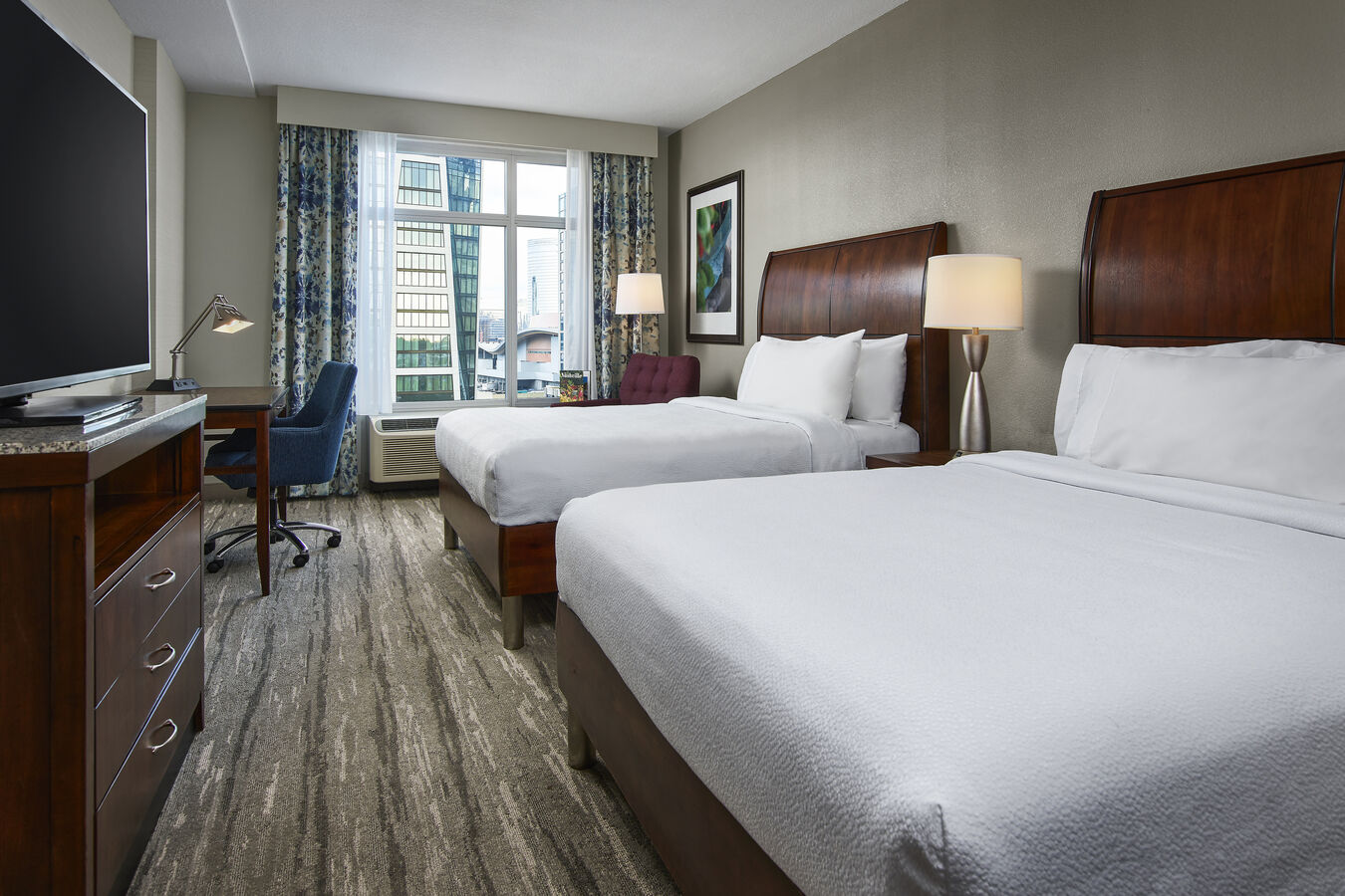 Two Beds, HDTV, Armchair and Work Desk in a Guest Room with City View