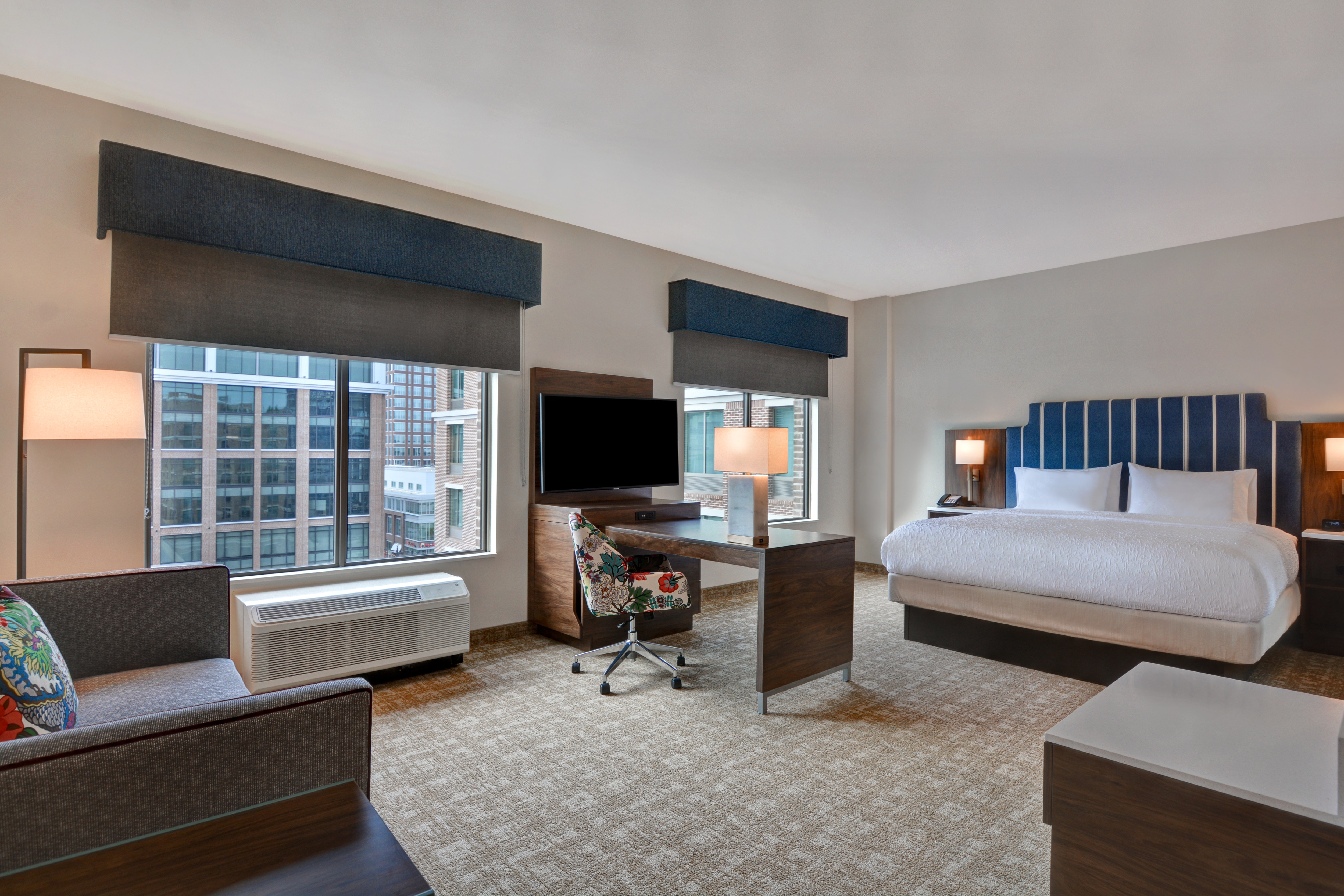 guest room with lounge area work desk television windows and bed