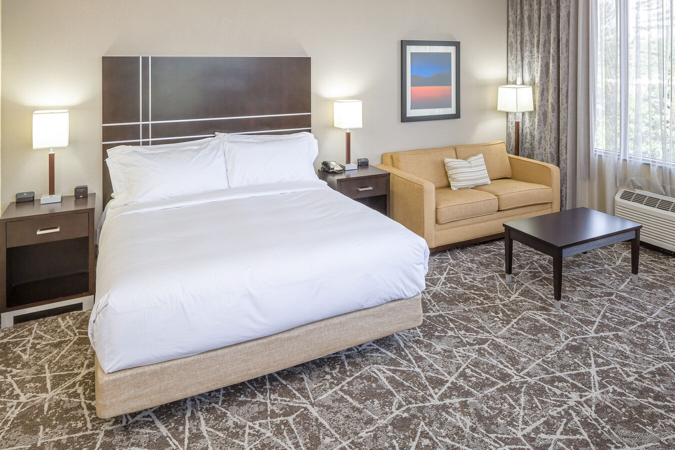 King Bed, Illuminated Lamps on Bedside Tables, Wall Art Above Sofa and Coffee Table in Deluxe Room