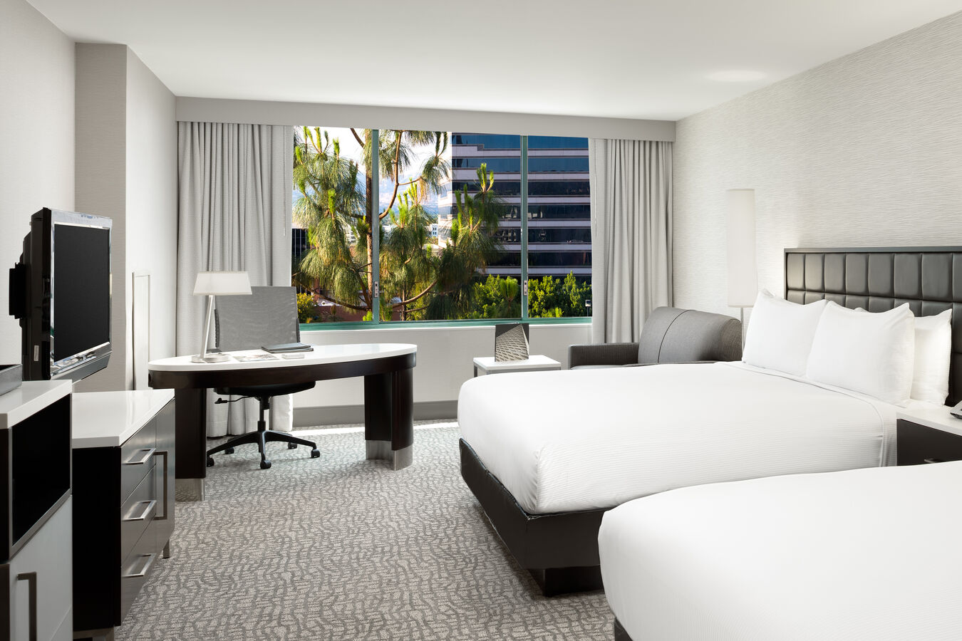 Two Beds, TV, Desk and Seating Area in a Guest Room with City View