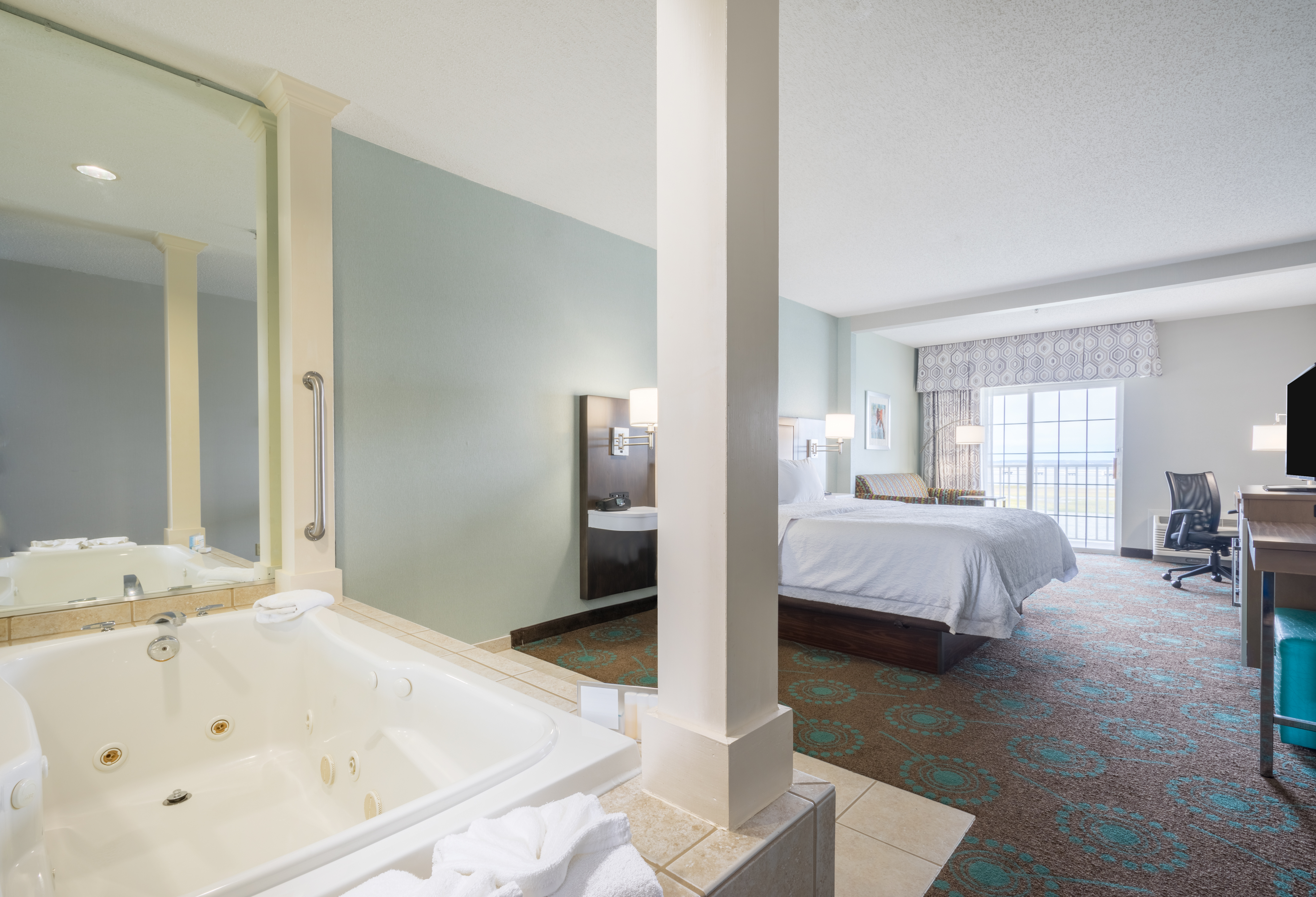 Whirlpool by King Bed and Bedside Tables Facing TV and Work Desk With Sofa in Corner by Window