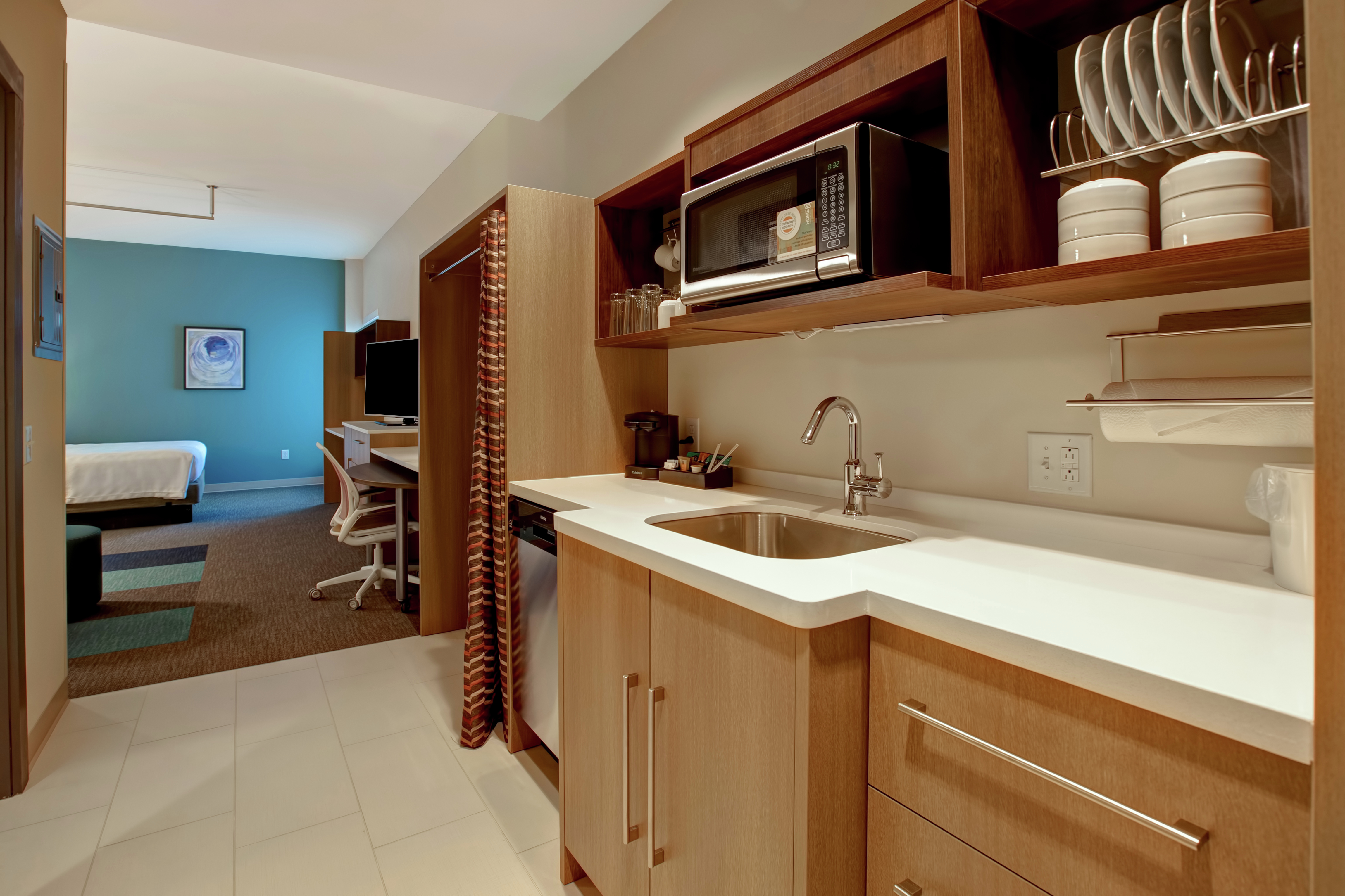 guest room showing a kitchen leading to the bed work desk and tv