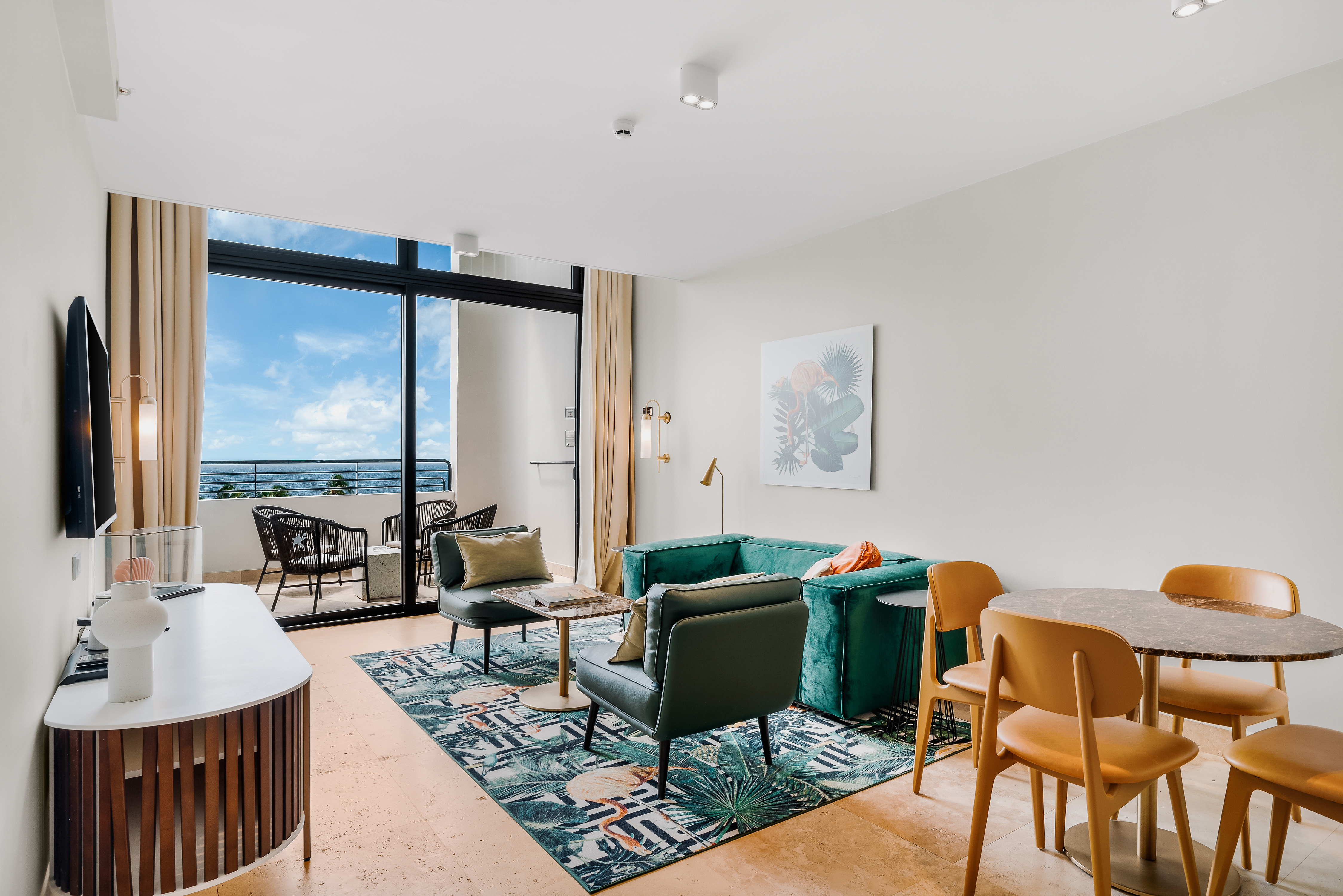 Lounge area with green couch and table and chairs plus view of balcony