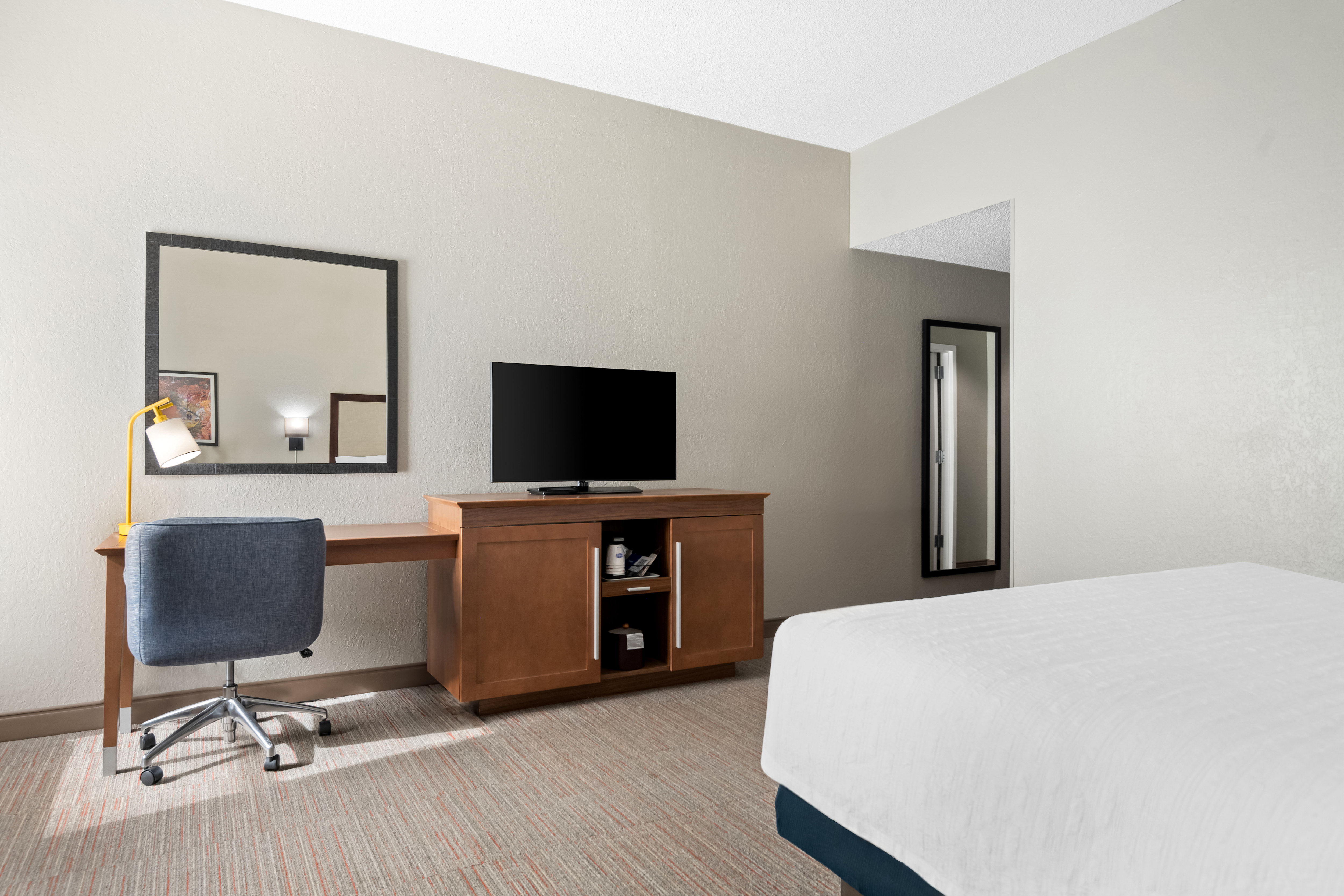 guestroom with king bed on right edge looking at tv and work desk area