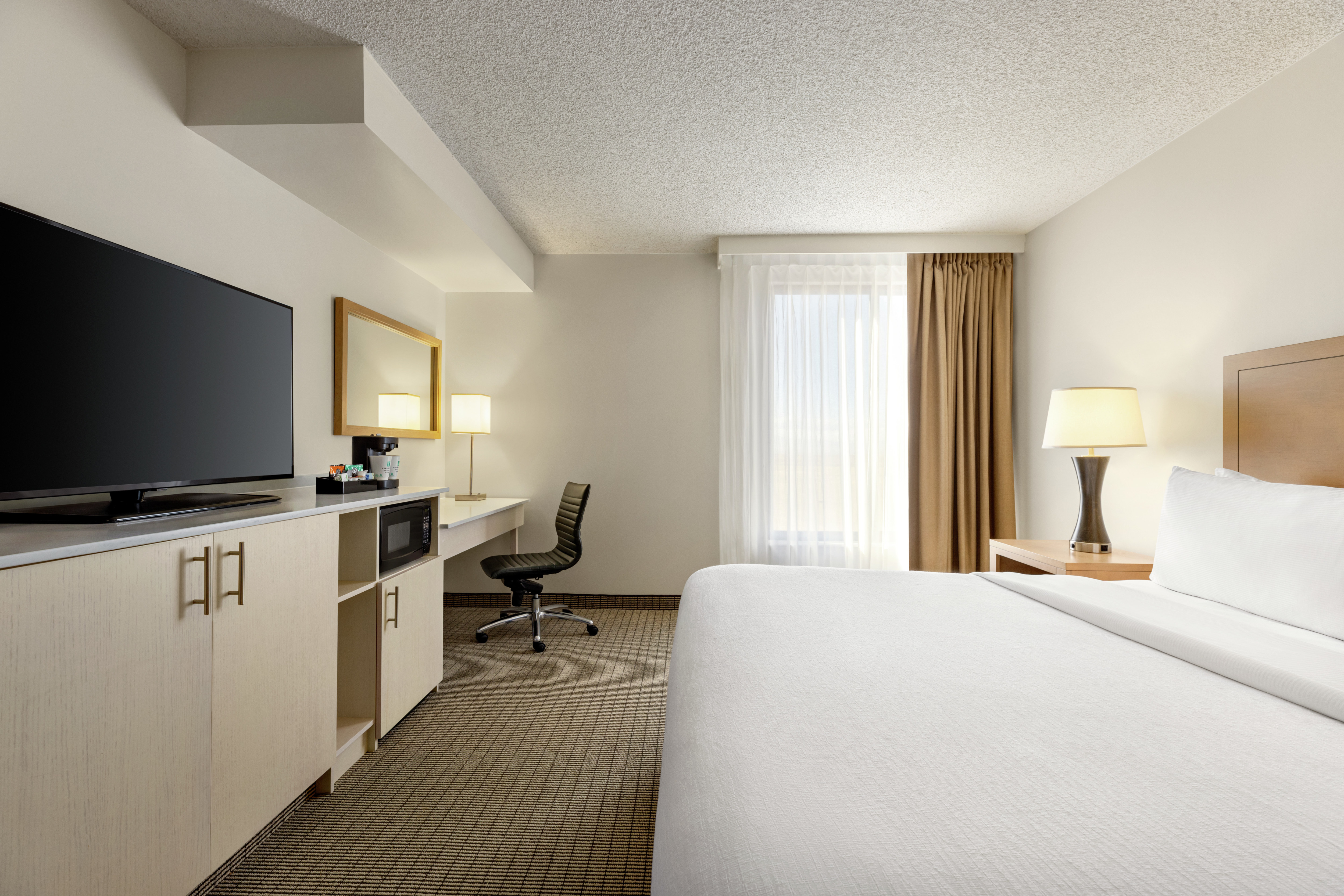 Bright studio suite featuring comfortable king bed, work desk, and TV.