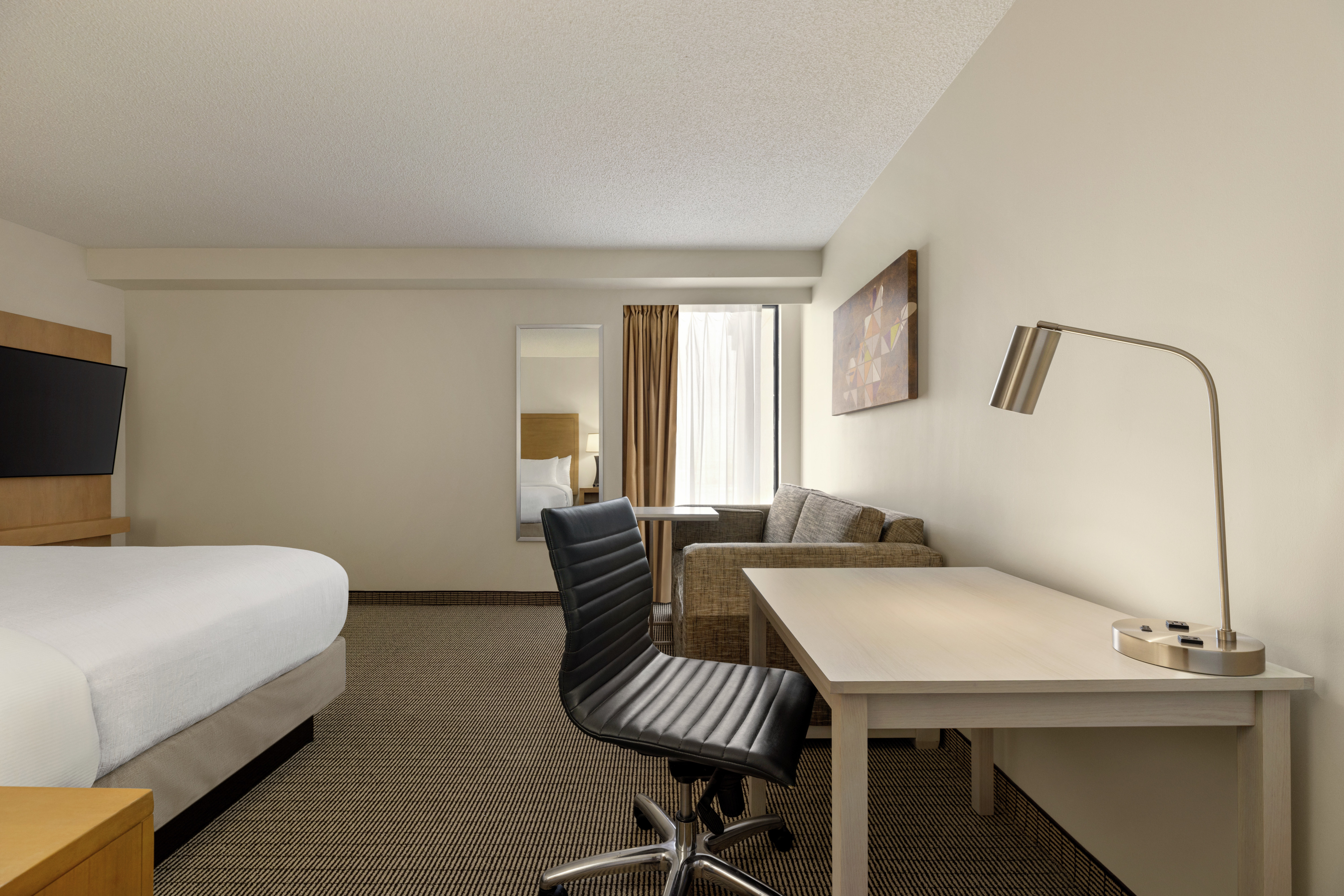 Spacious studio featuring comfortable king bed, work desk, TV, and pullout sofa bed.