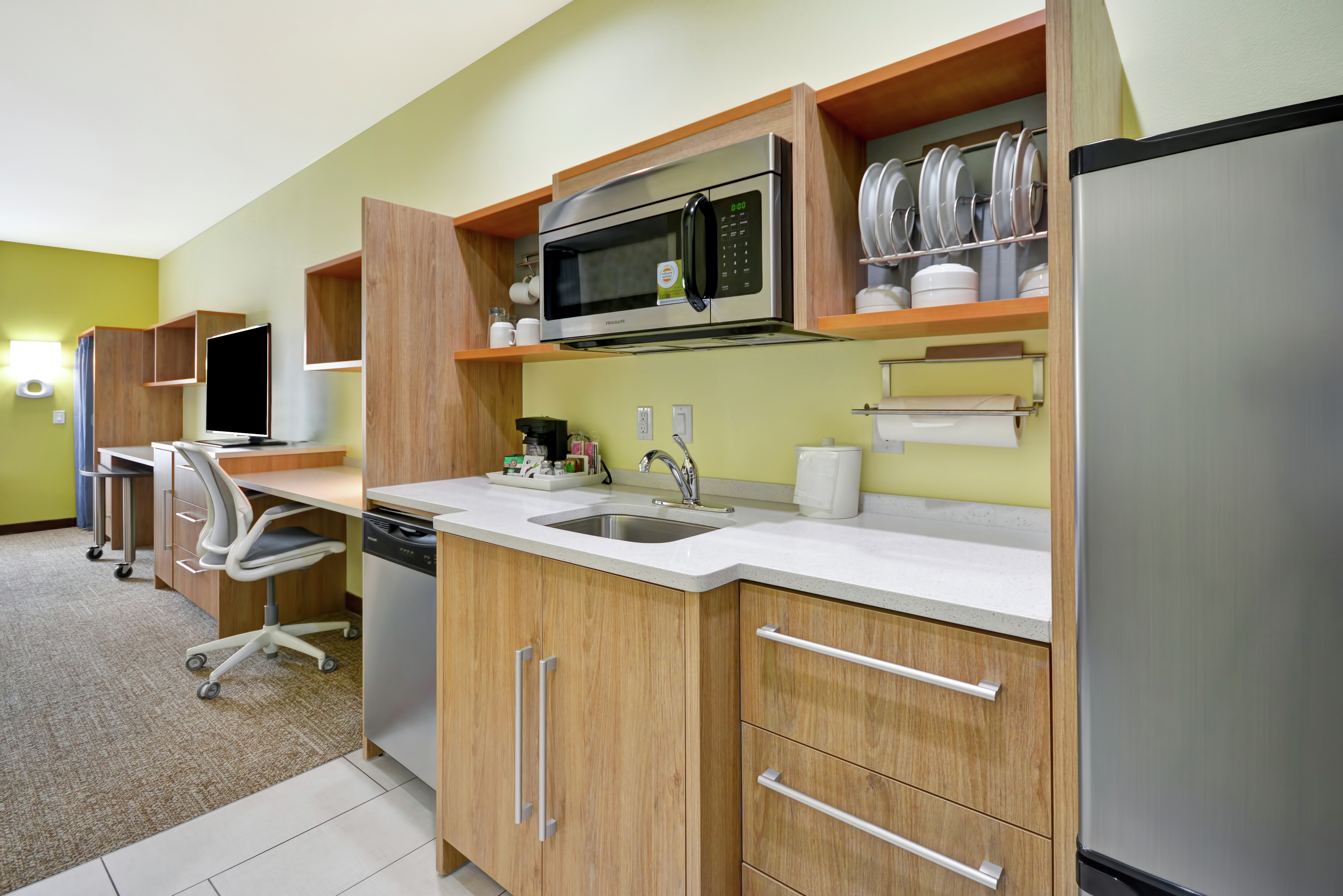 Kitchen with fridge and microwave. Working desk in background