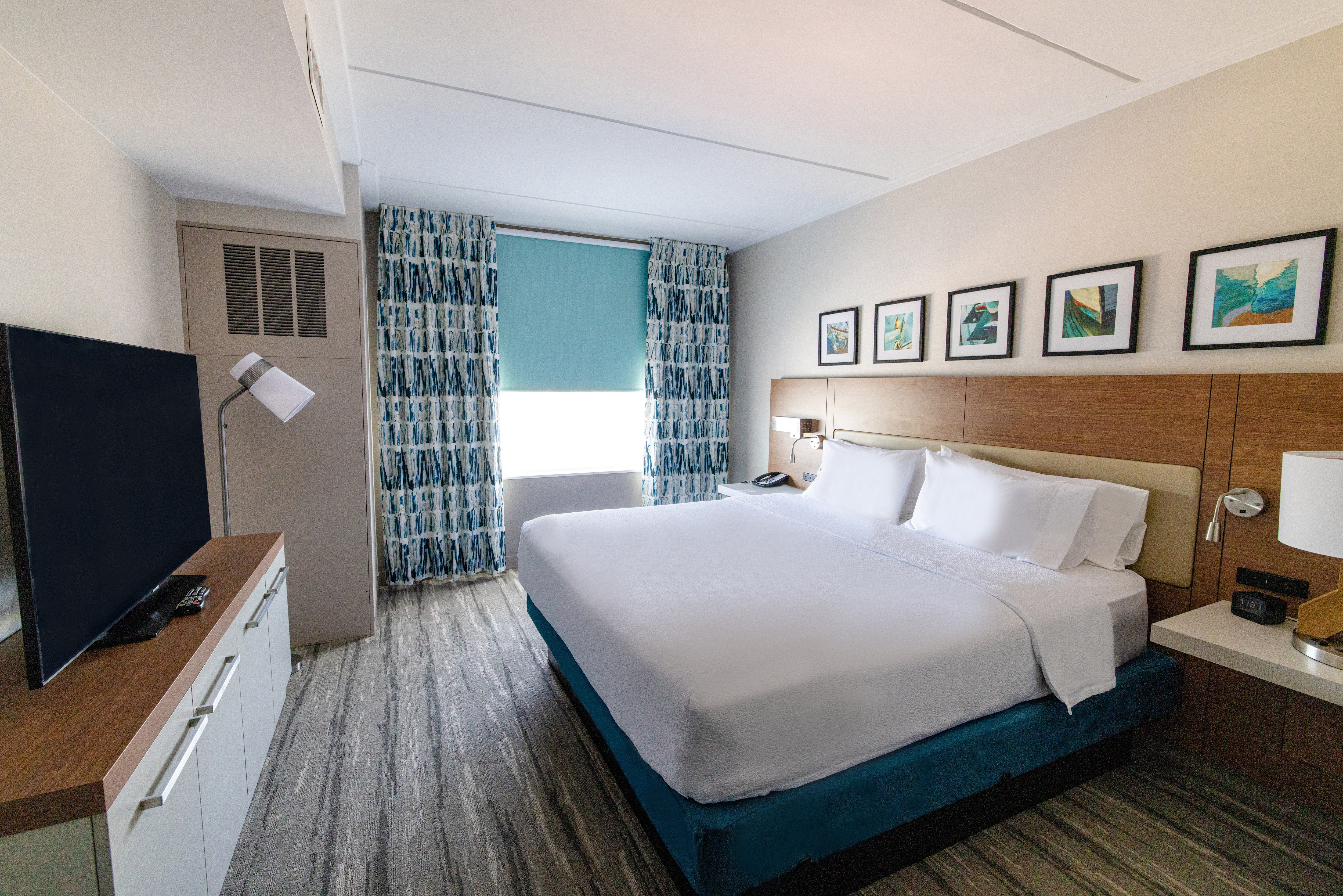 King bed with bedside tables, tv and wall art