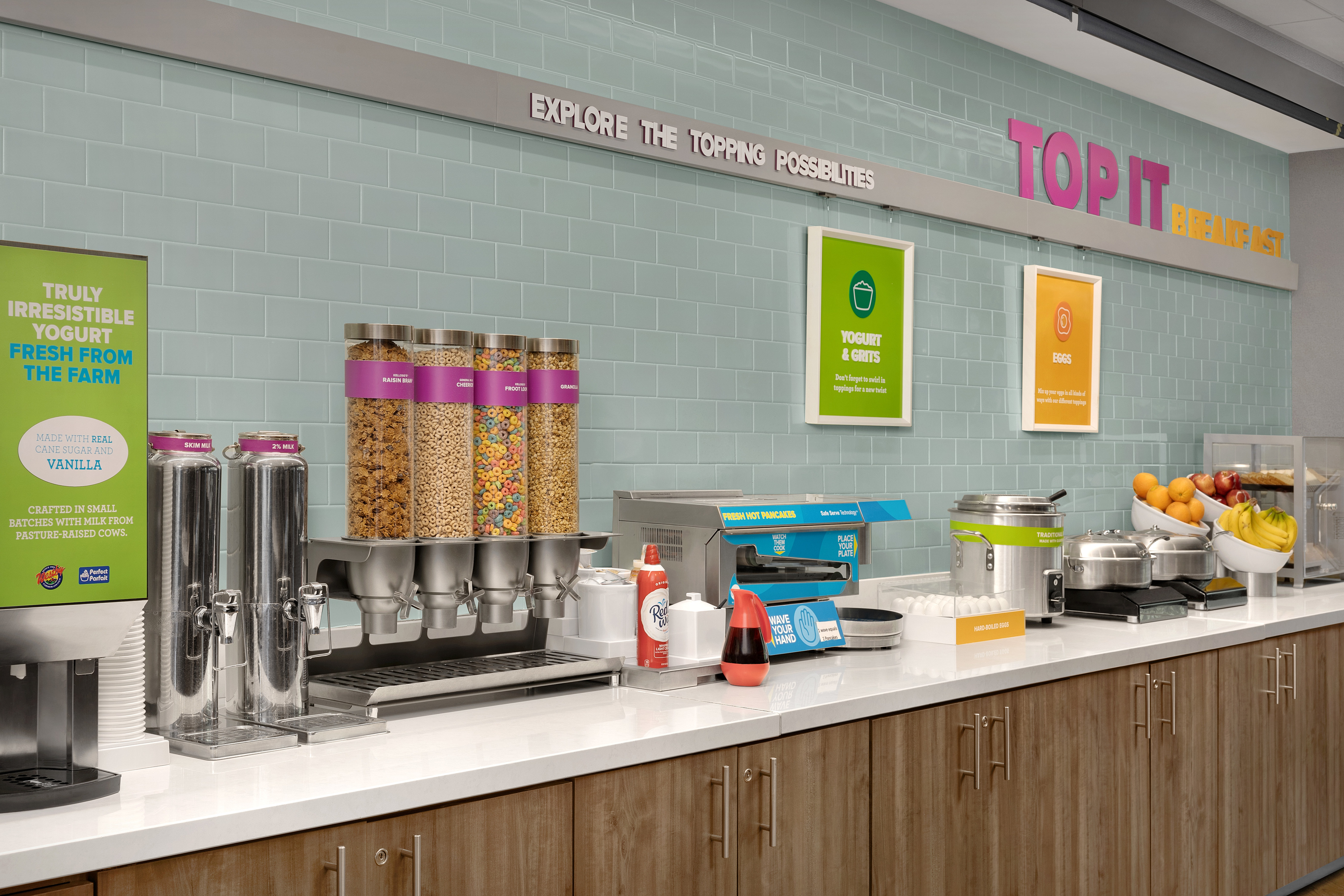 Close-up of breakfast selection with cold and hot beverages, pancake maker, grits and fruit