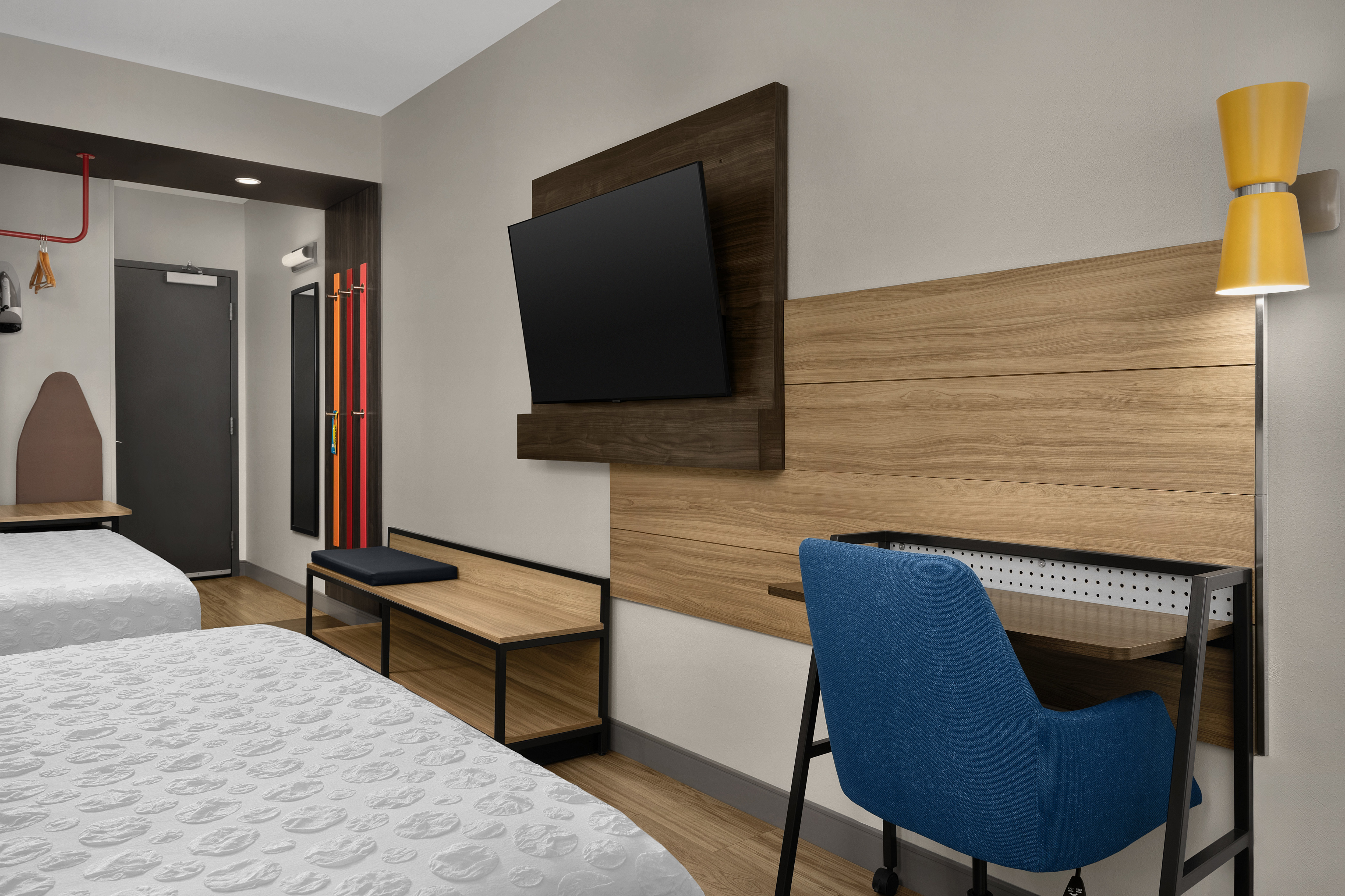 Guestroom with two queen beds, flatscreen tv, desk with chair and view to entrance.