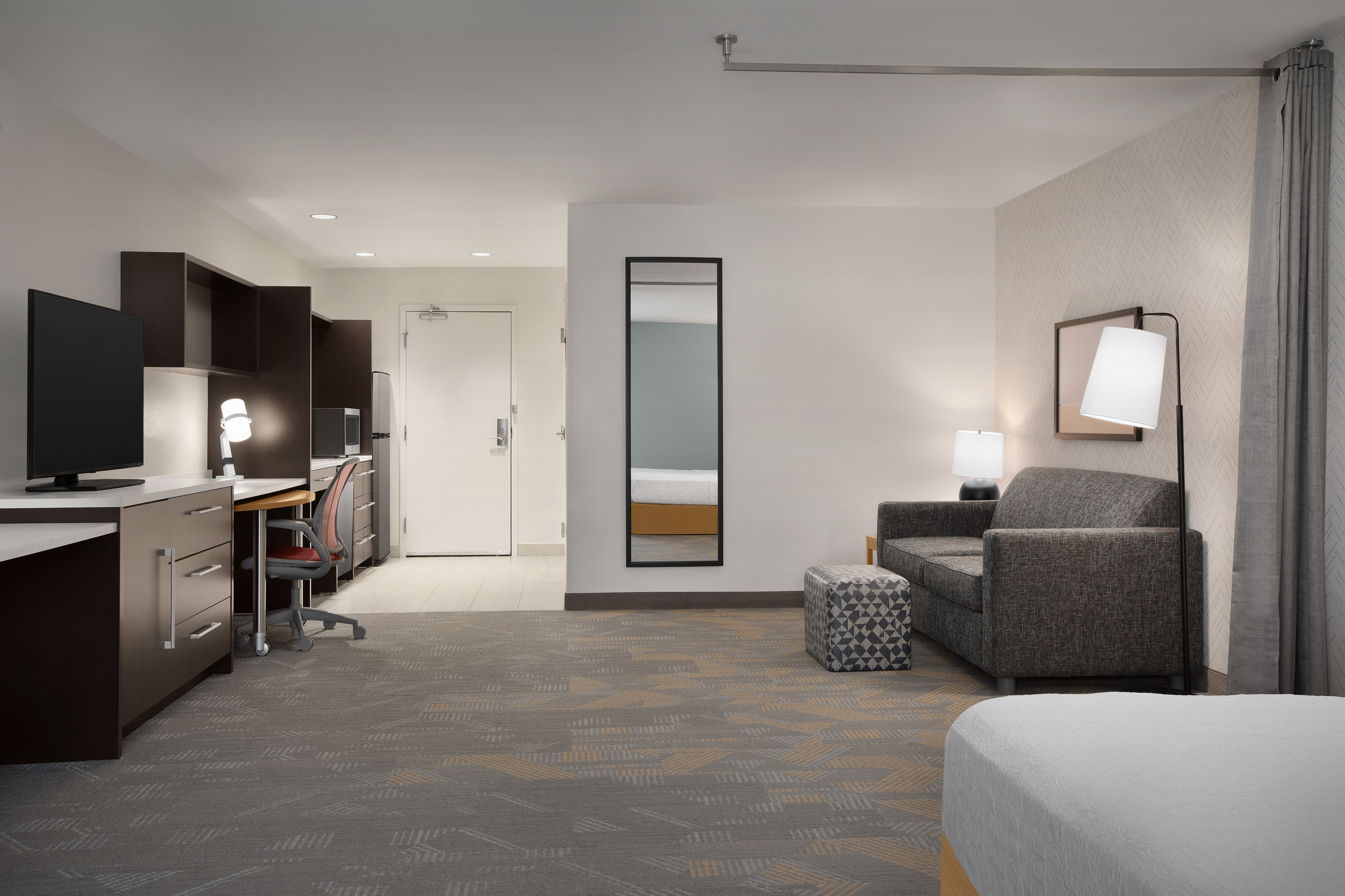 Accessible Studio Suite Lounge Area with Dresser, TV, Work Desk, Lamps, and Sofa