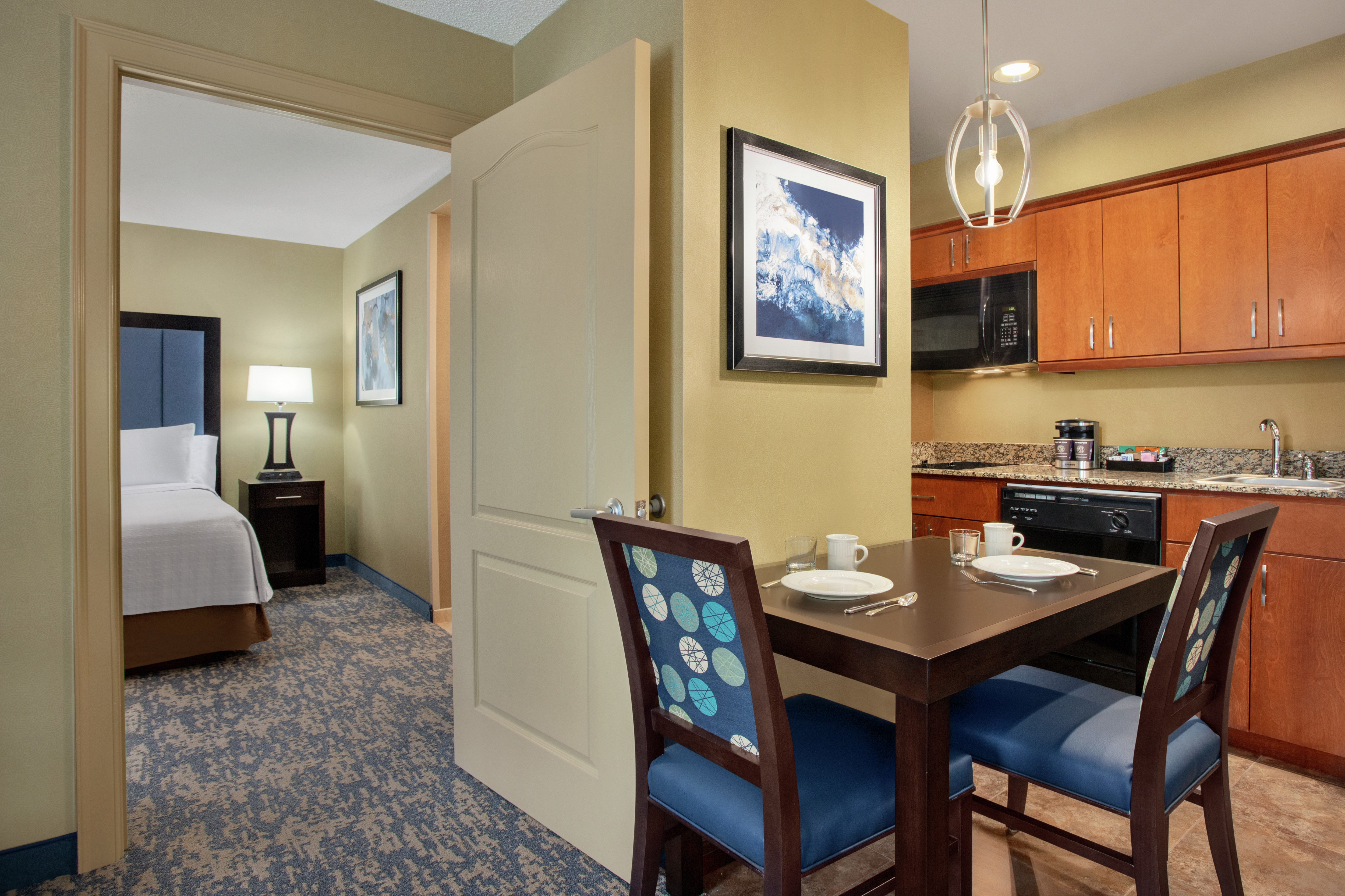 Spacious living area in suite featuring a fully equipped kitchen, dining table, and private bedroom with king bed.