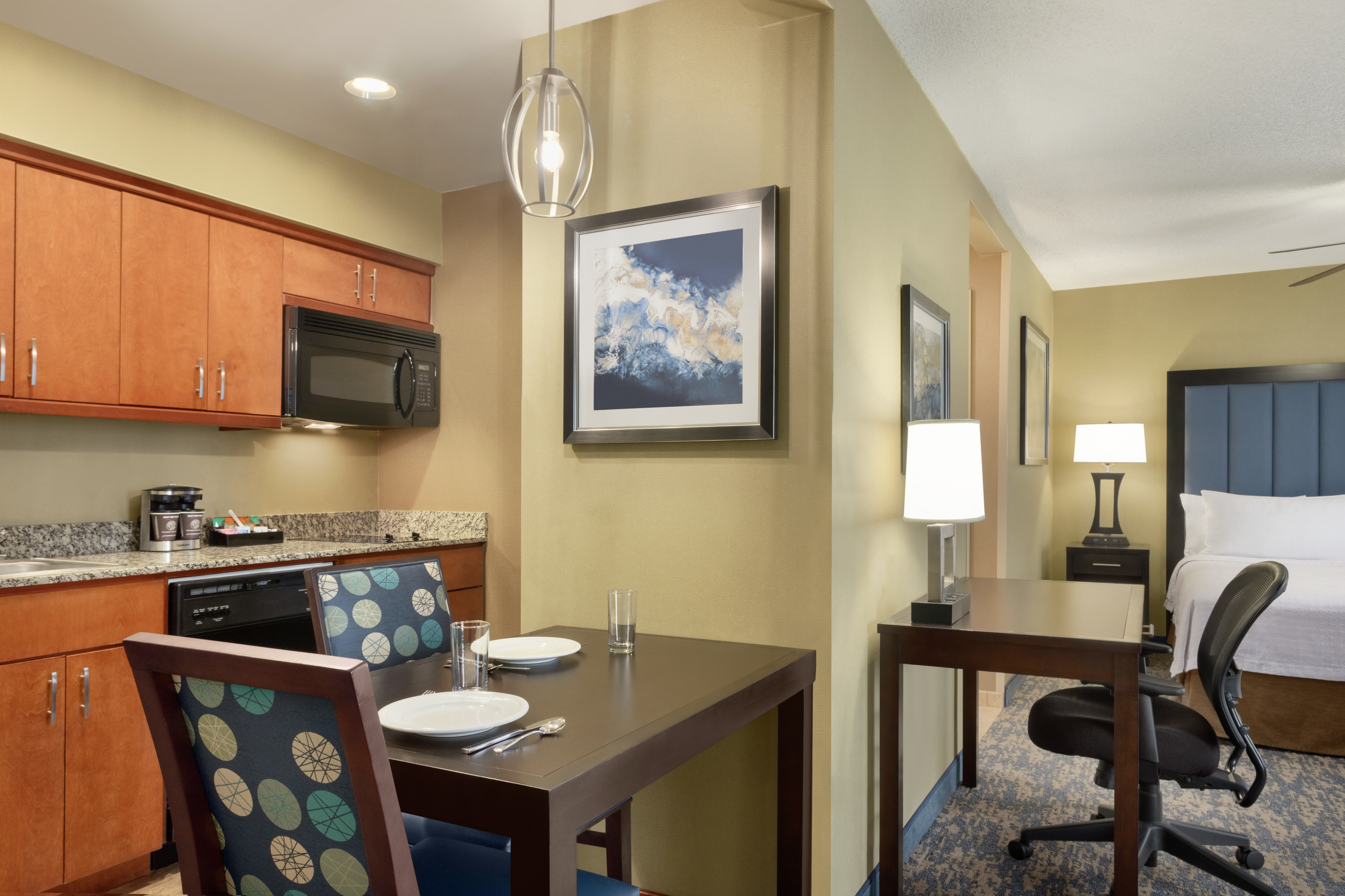 Spacious studio suite featuring a fully equipped kitchen, dining table, work desk, and comfortable king bed.