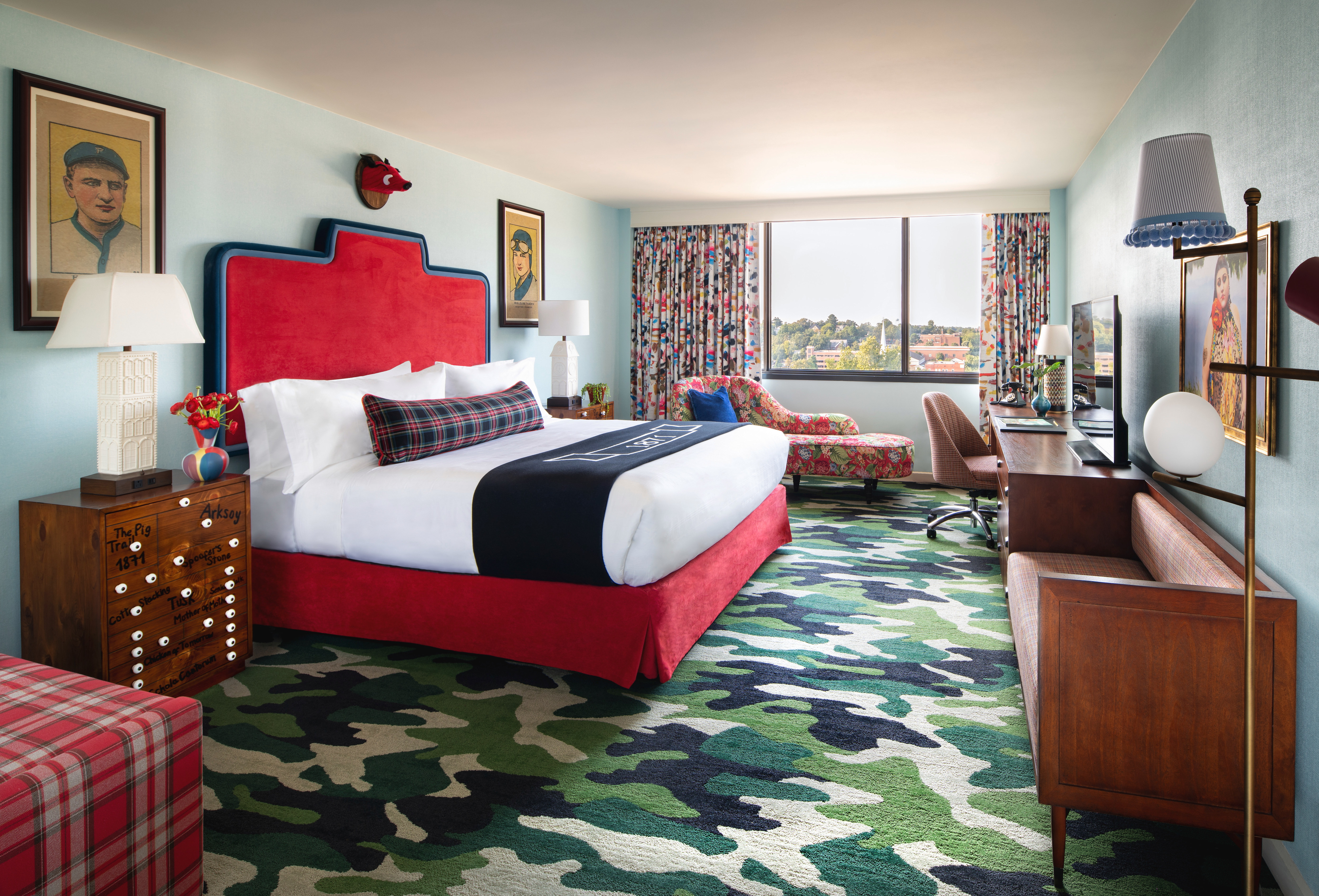 Bed in room with chairs, work desk and art on walls