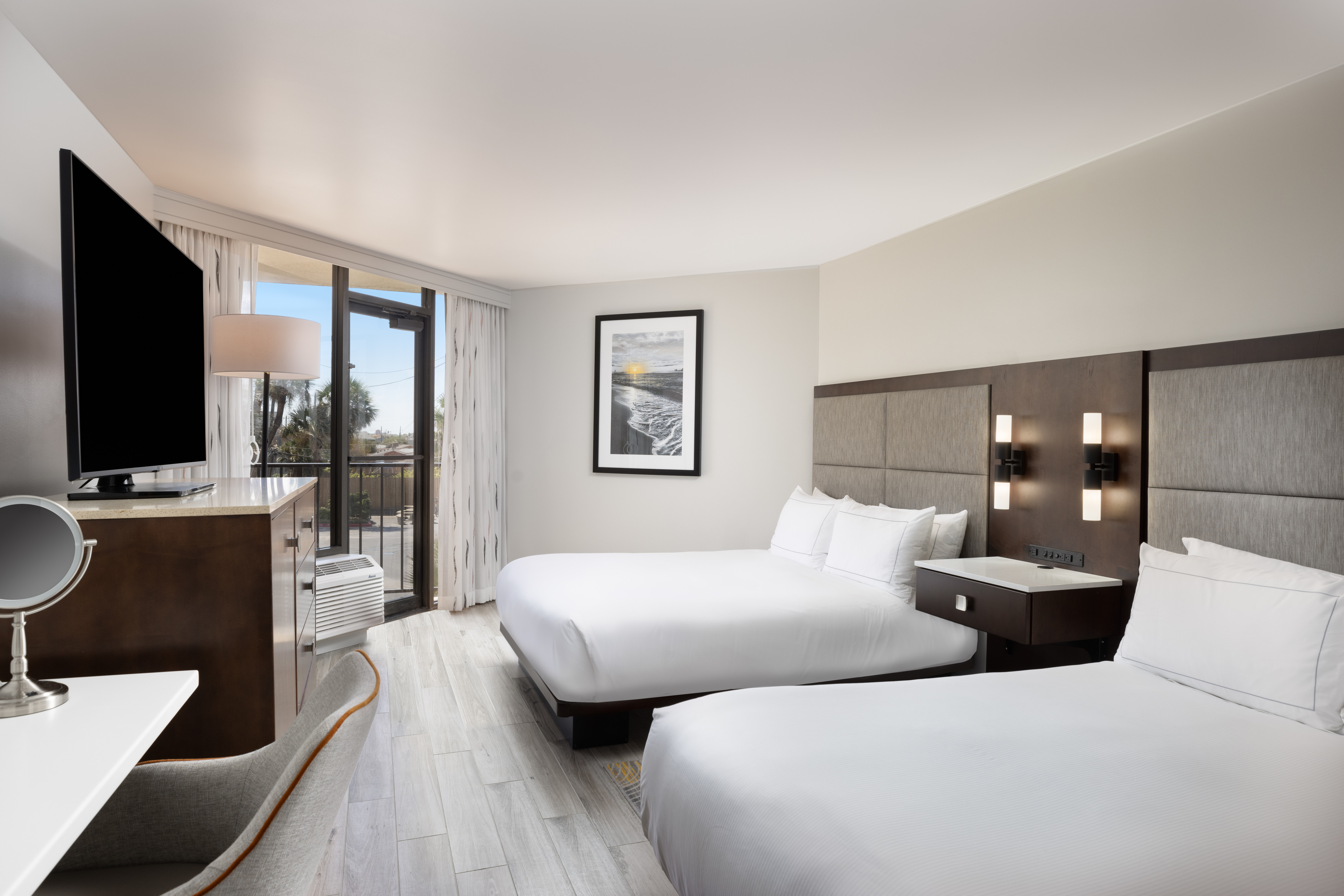 Accessible hotel room with two queen beds, large HDTV, vanity area and door accessing private balcony