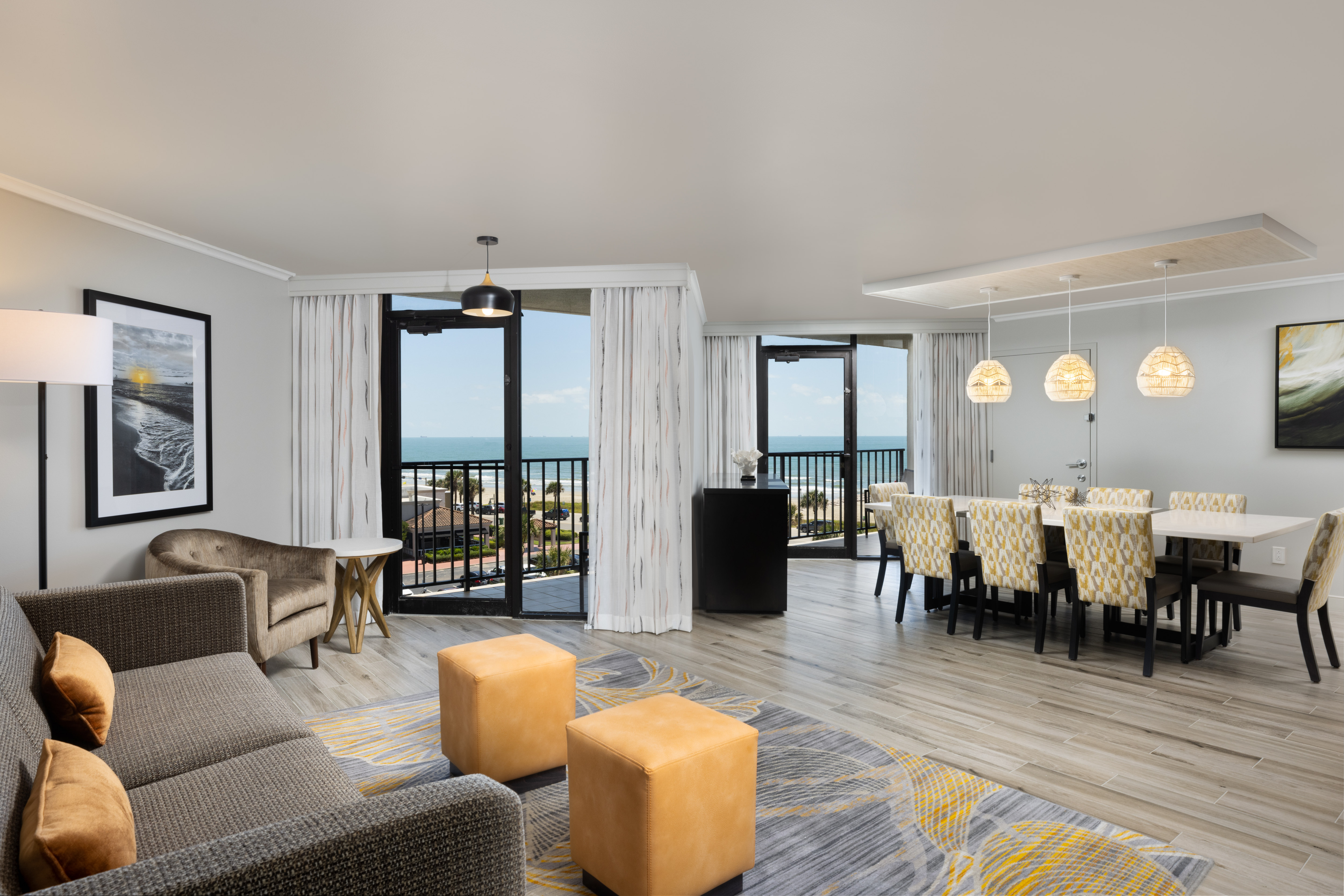 Living area with table for eight, a sofa, and two doors to balcony.