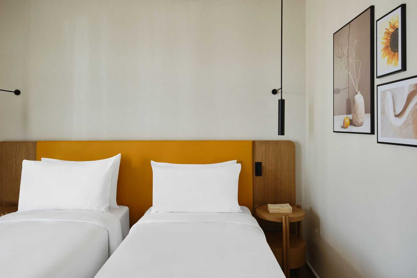 Two beds in room with light and art on wall