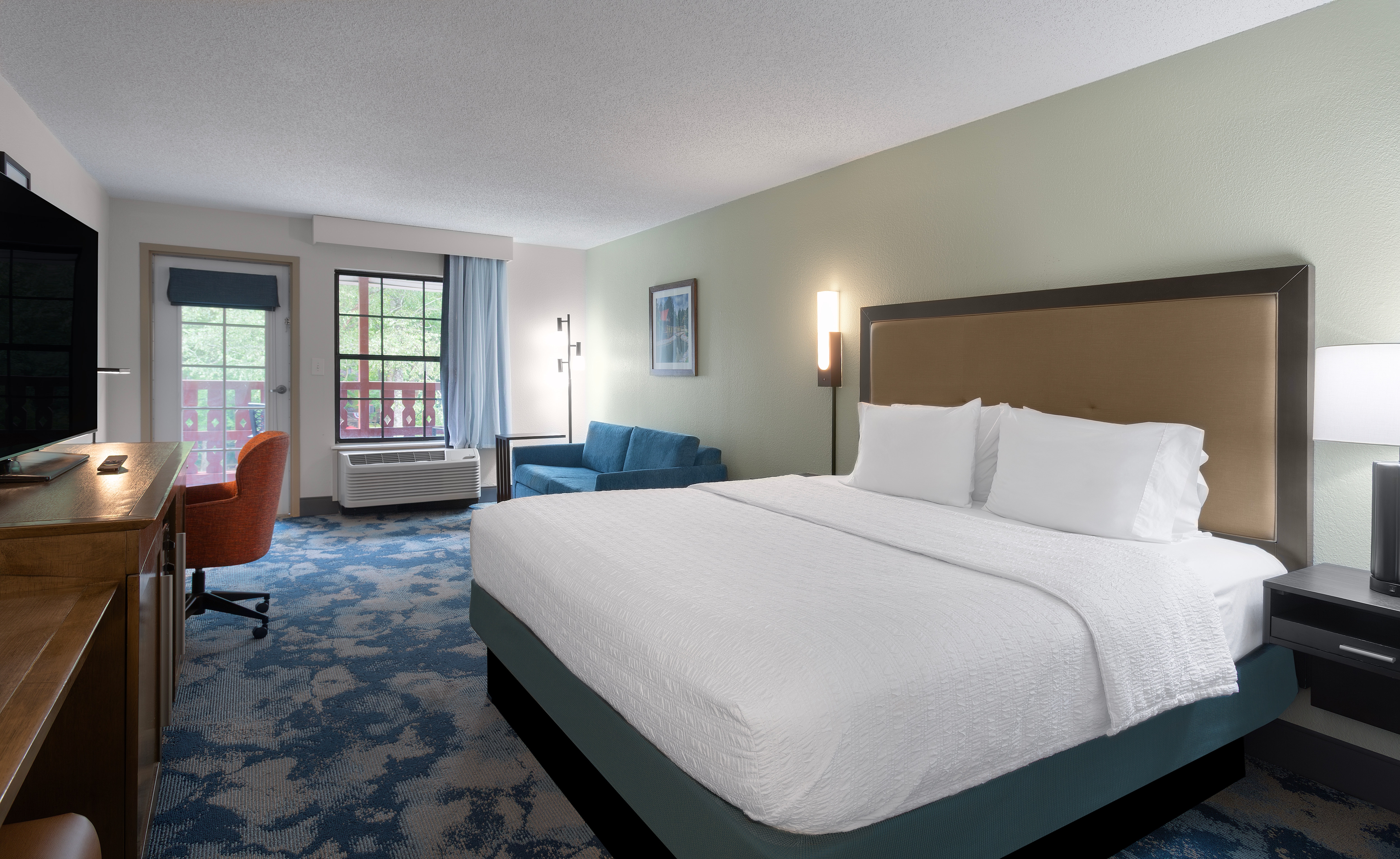 One bed guest room with television work desk and chair with exterior door