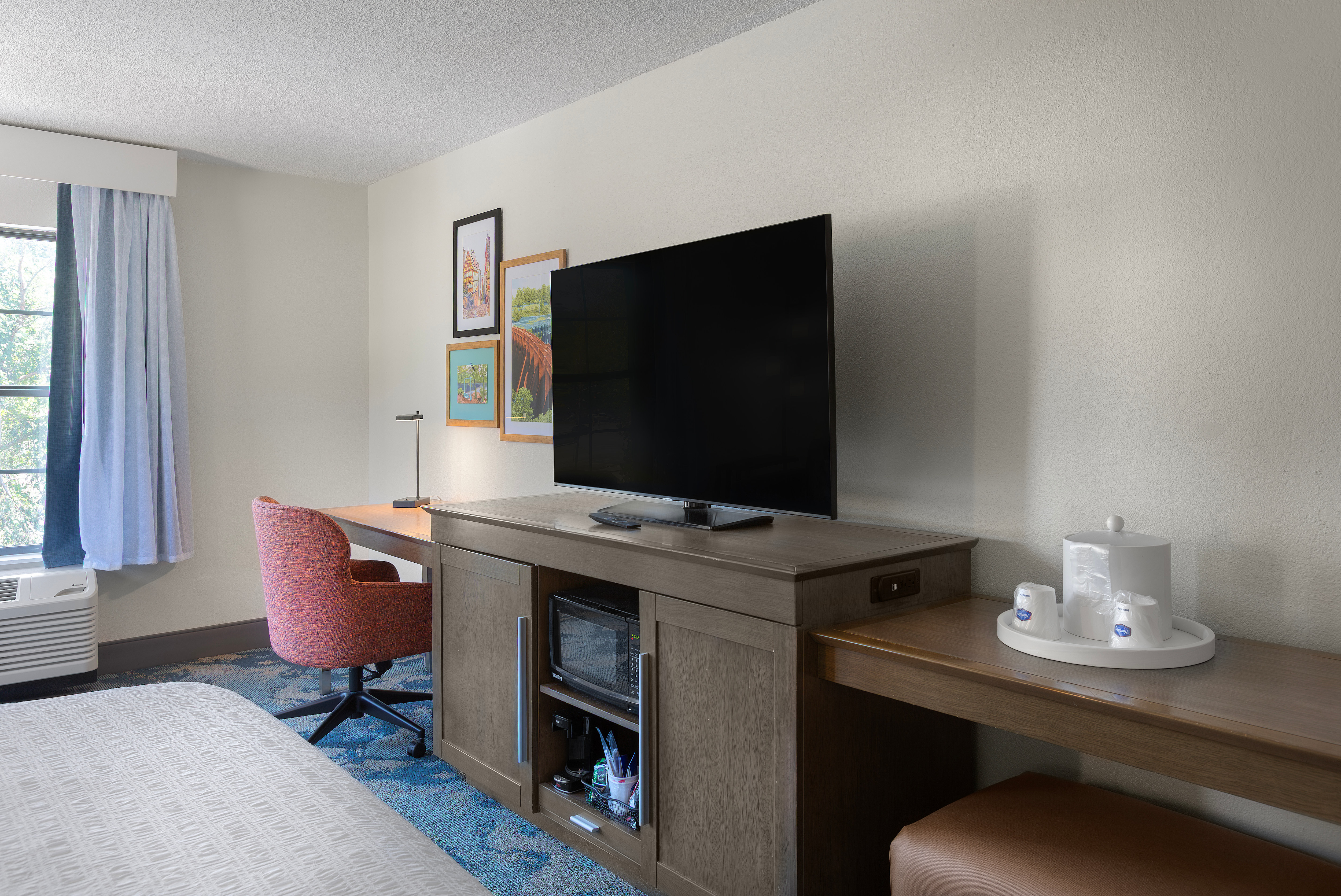 Television on cabinet with work desk and chair in a guest room 