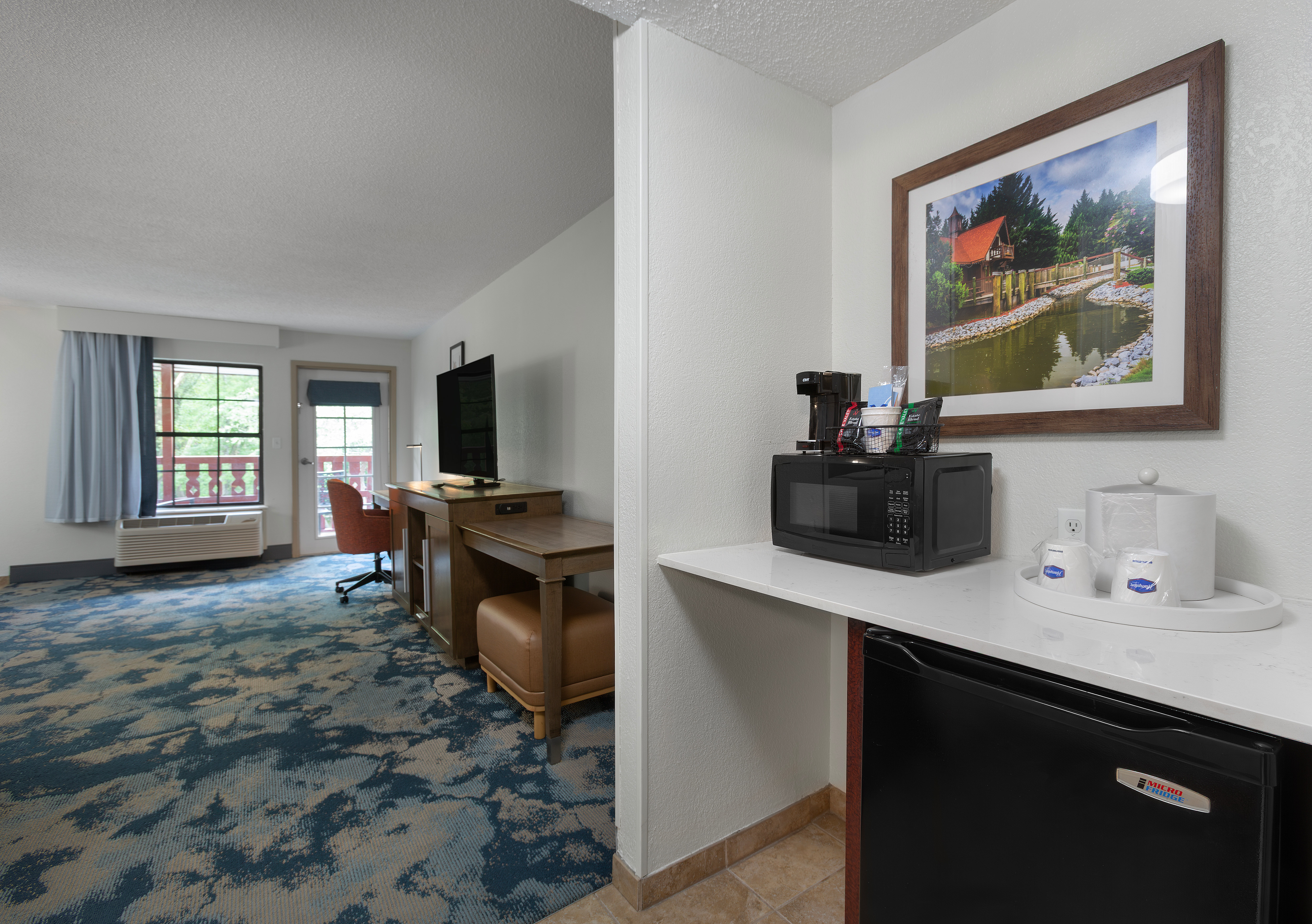 Guest room with desk chair television coffee maker and microwave