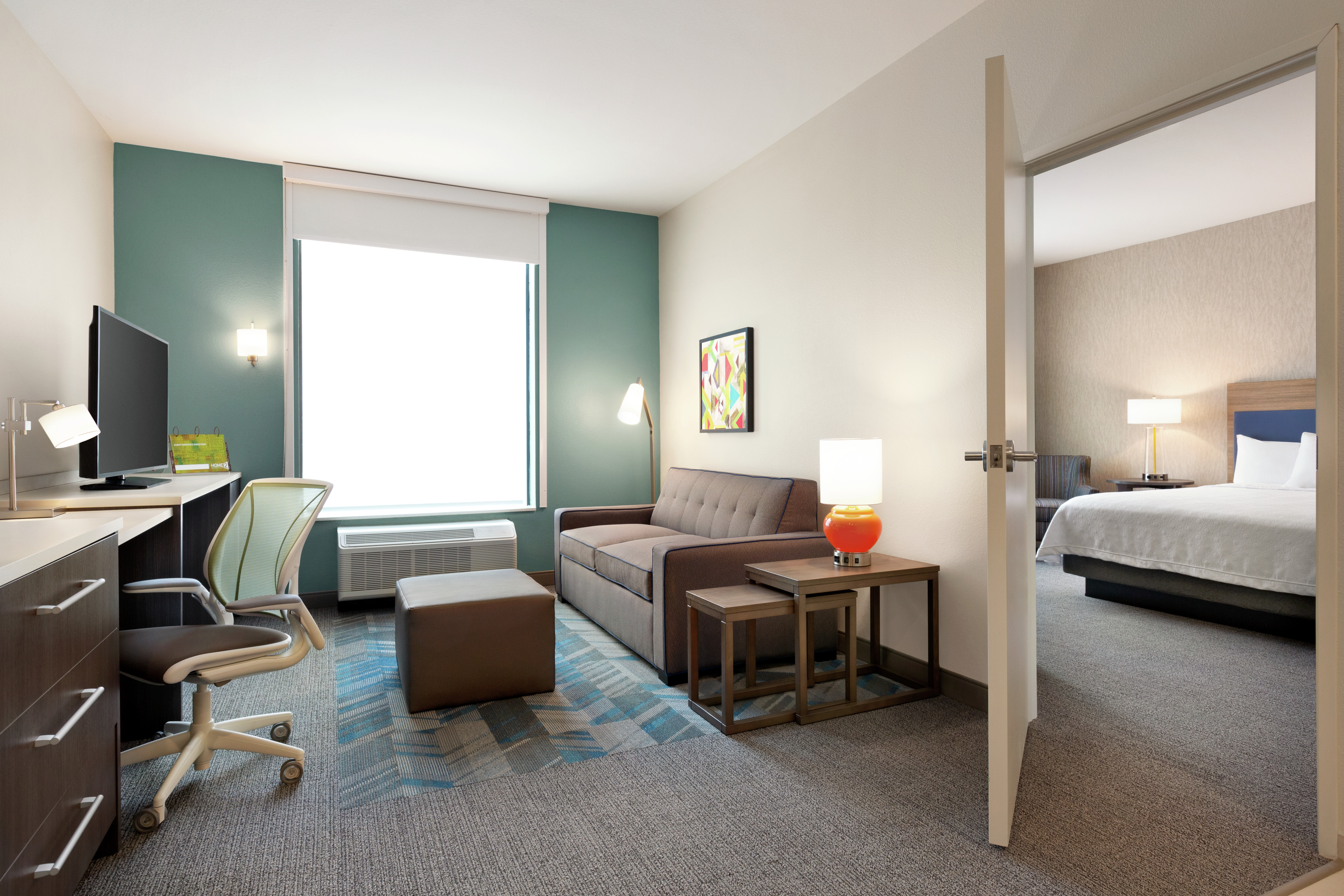 Spacious accessible suite featuring living area with sofa, TV, work desk, and private bedroom with king bed.
