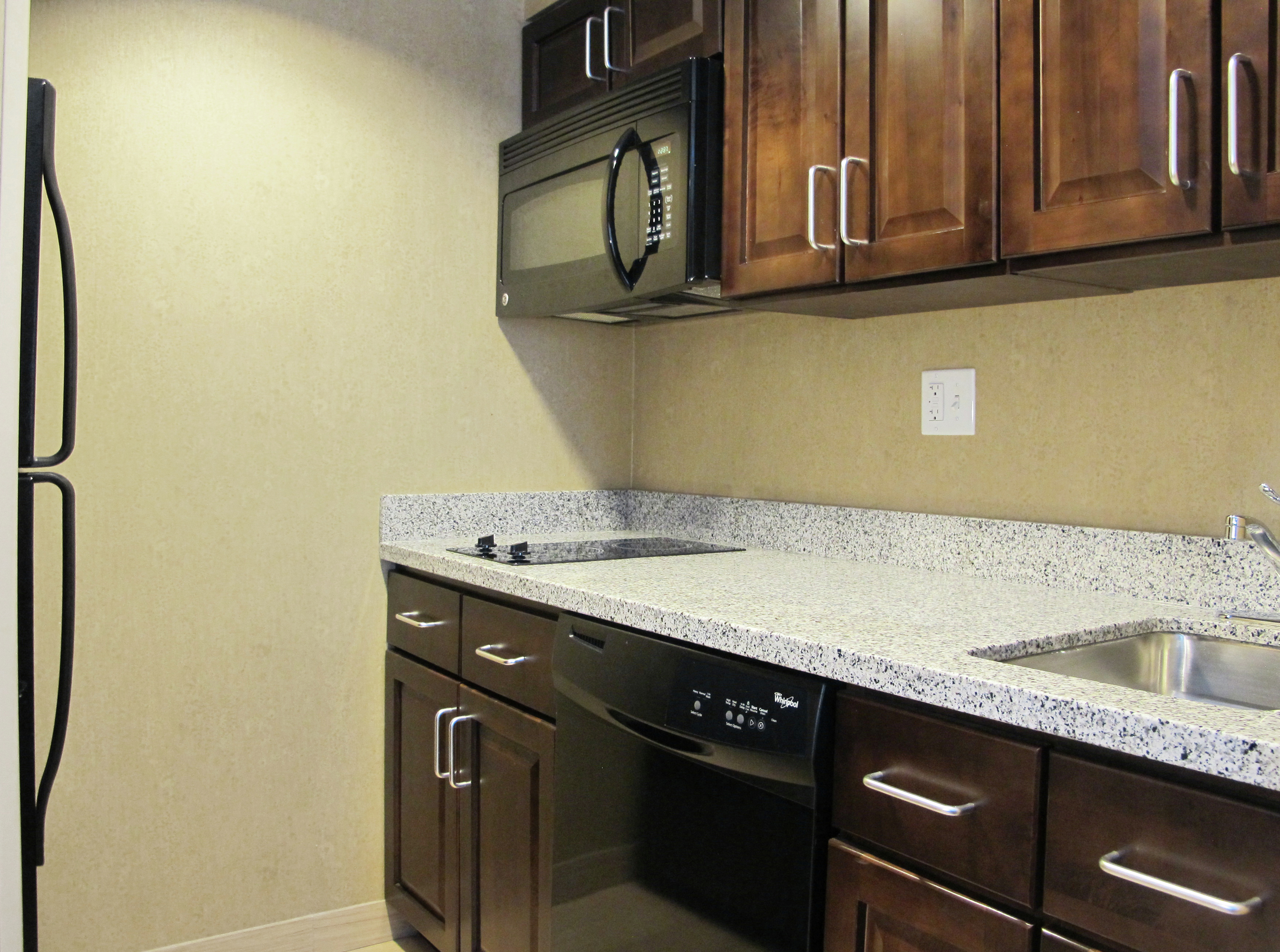 Suite Kitchen with Dark Cabinets and a Microwave Oven