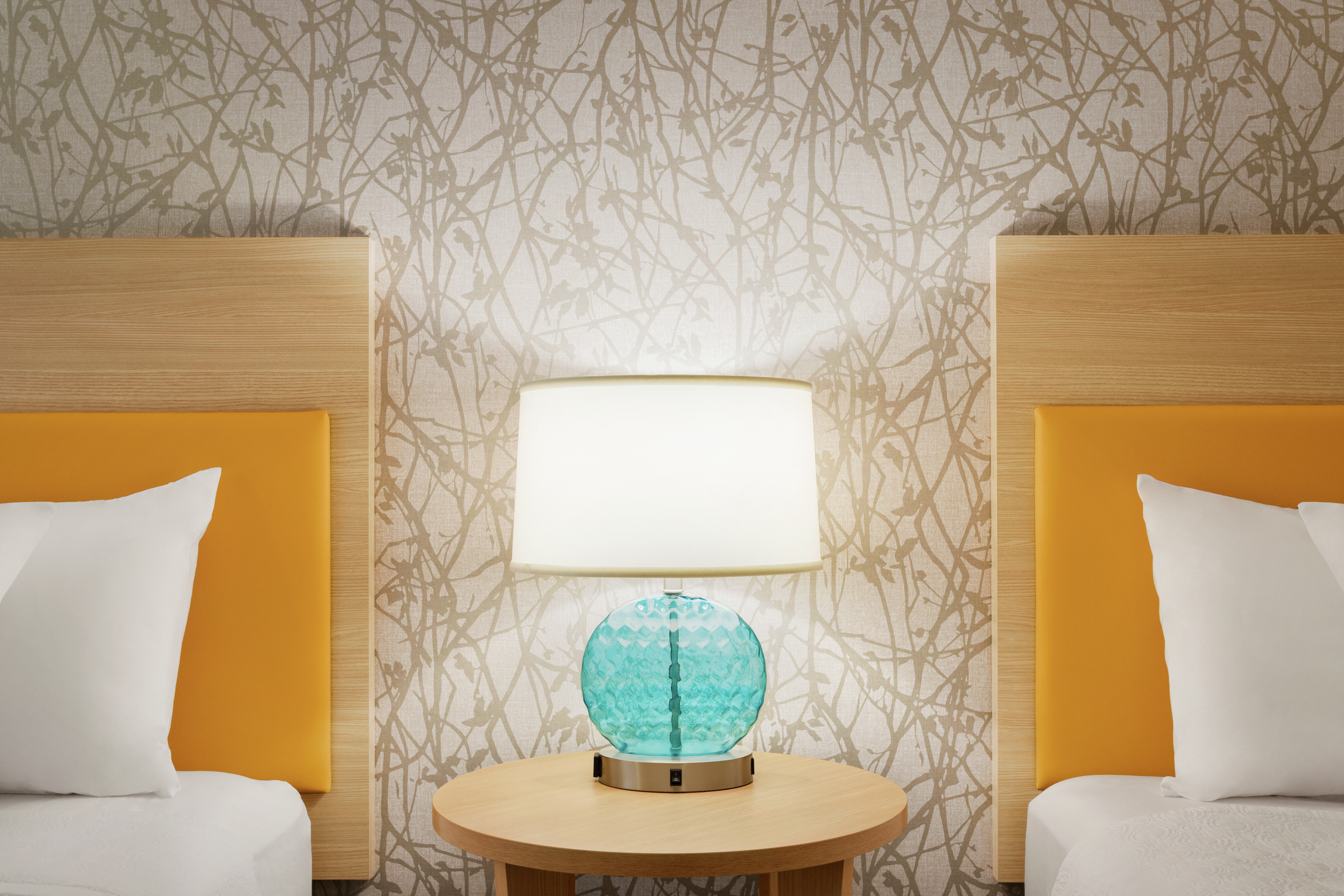 Guestroom detail featuring two queen beds, side table with lamp, and beautiful textural wallpaper.