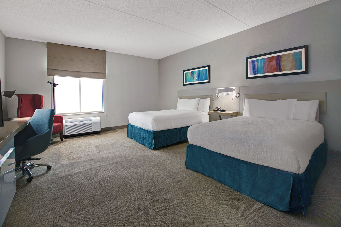 guest room with two beds work desk lounge chair and window