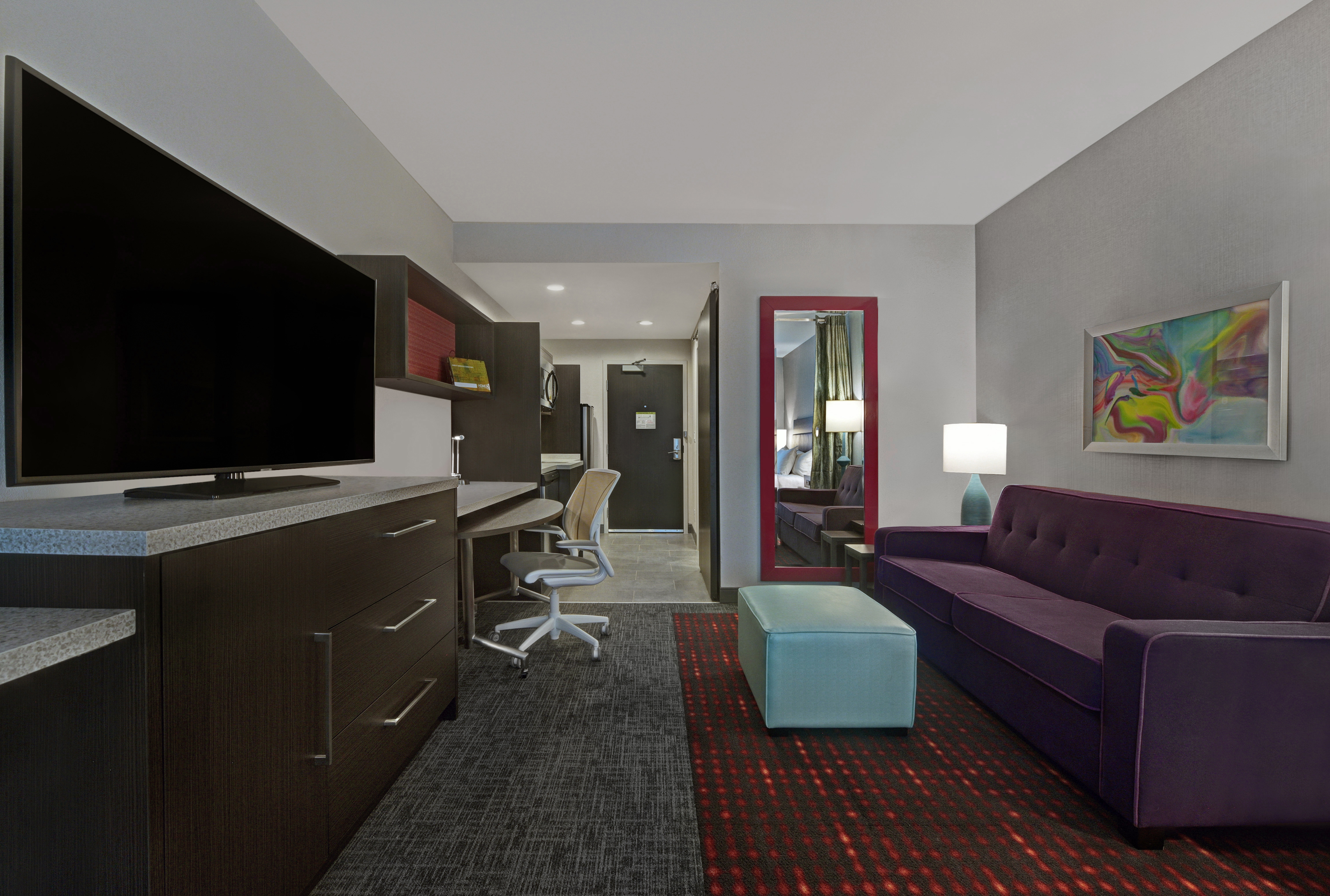 a guest room lounge area with television and view to the entry