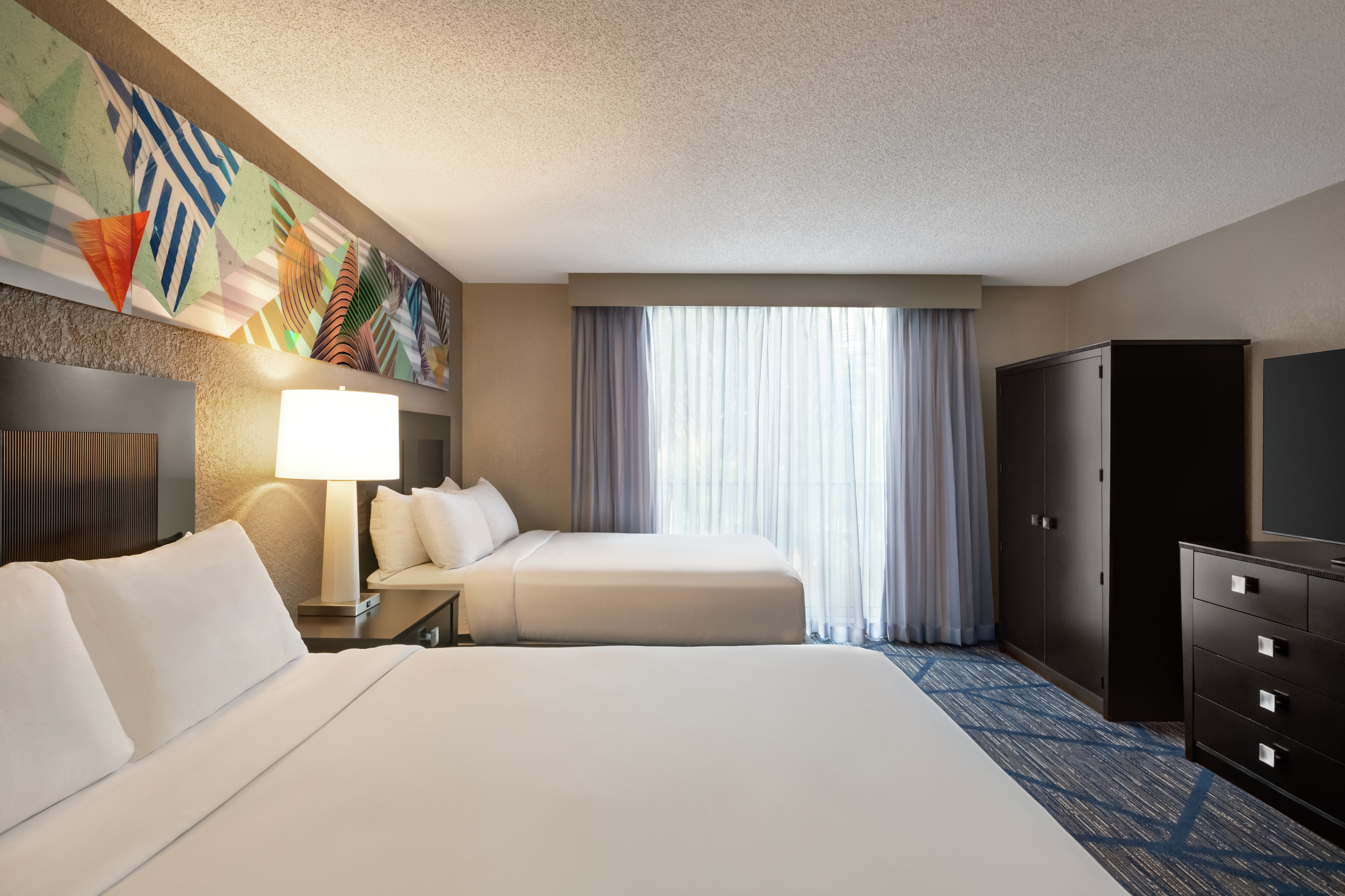 Spacious guest bedroom with two comfortable queen beds, television and large wardrobe