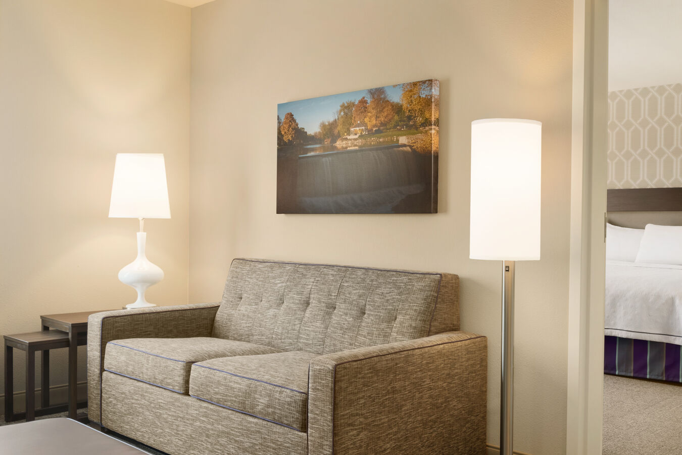 One King Bed Guestroom with Bedroom in Background and Lounge Area with Sofa and Footrest in Foreground