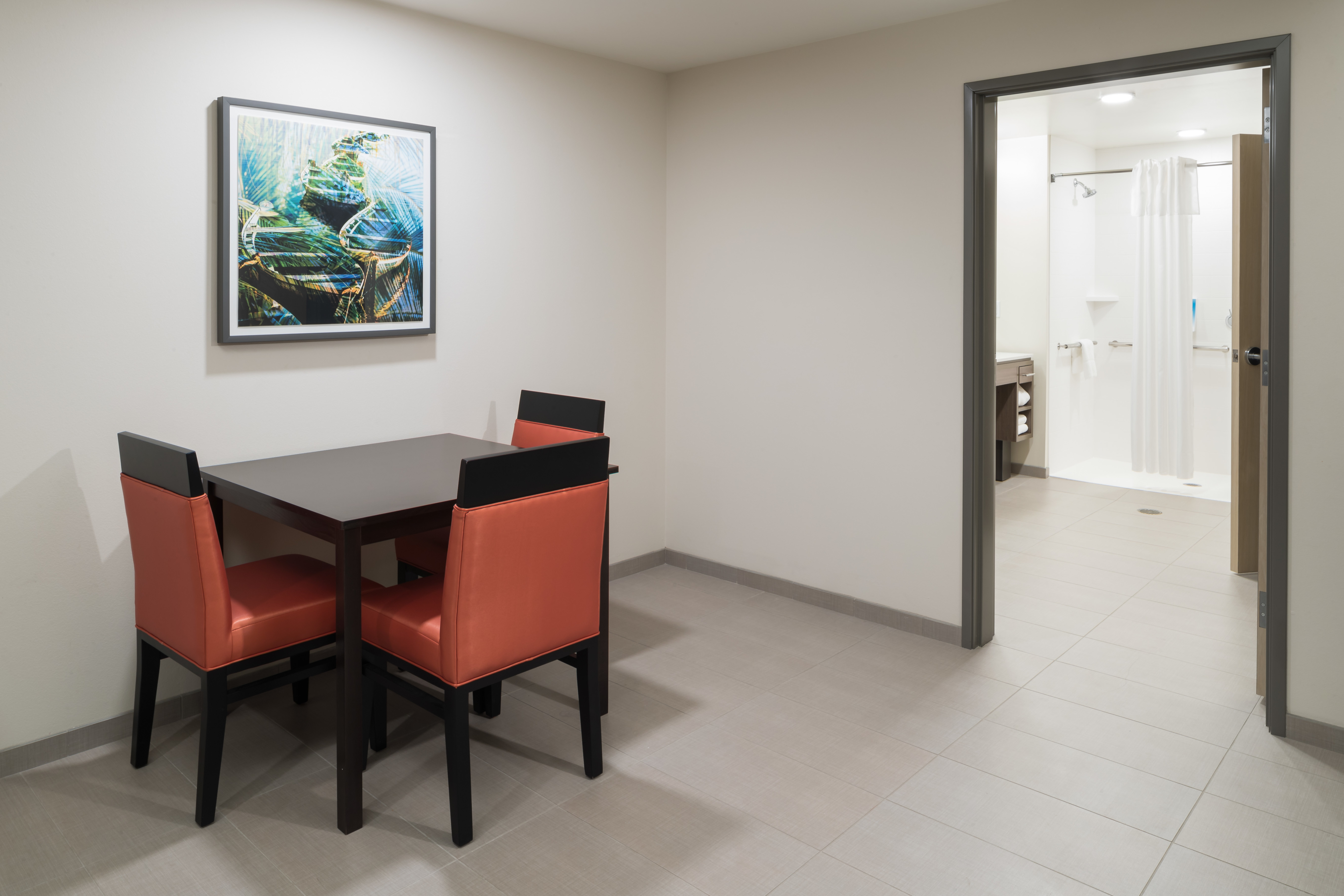 Table in Guest Room and Partial View of Bathroom with Roll in Shower