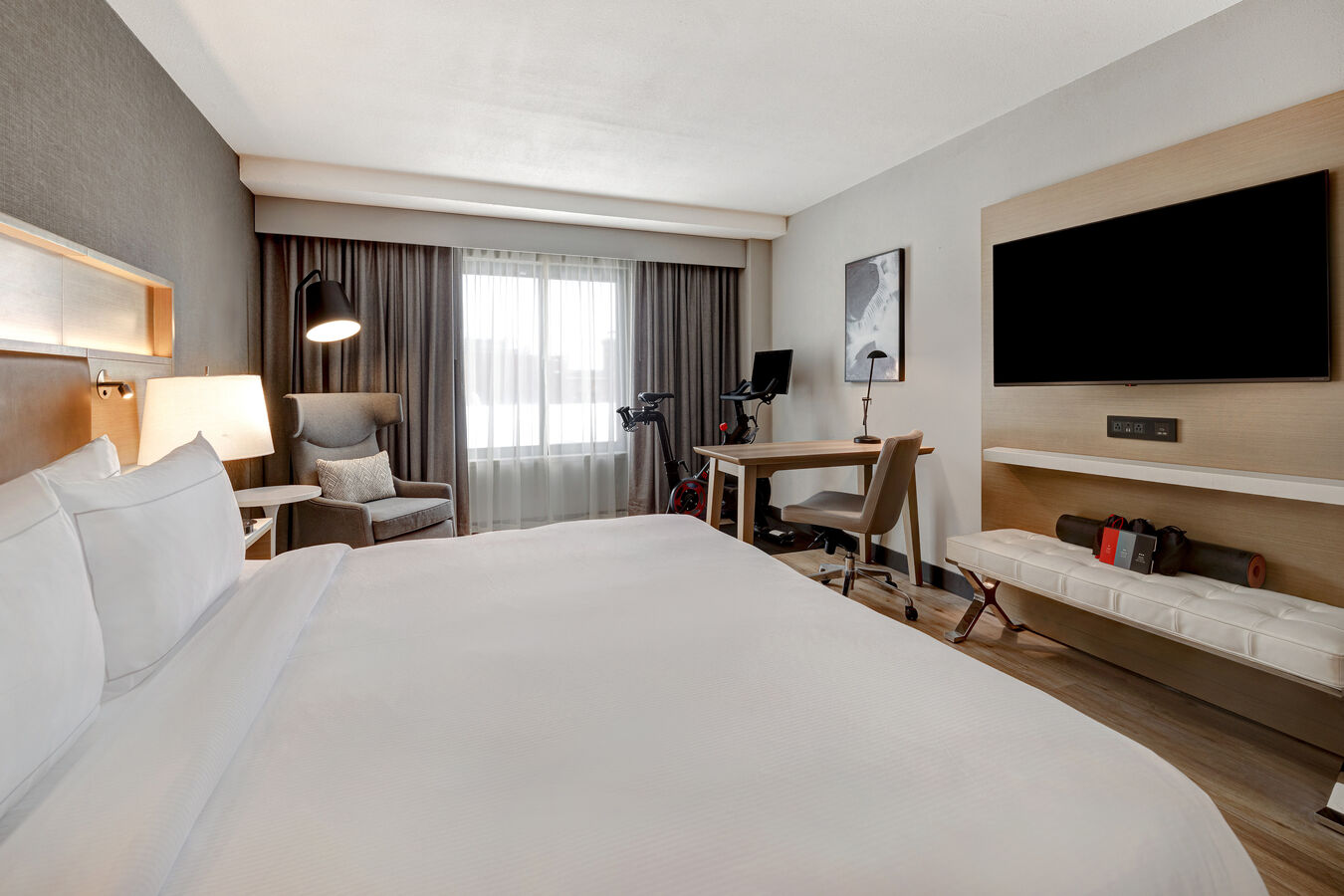 guest room with bed work desk tv and exercise machine