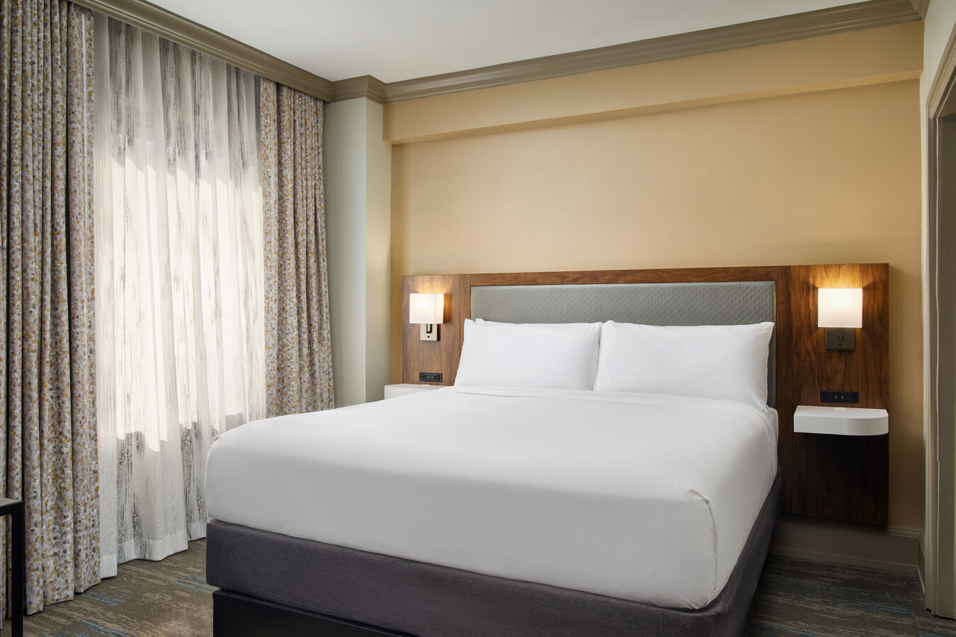 Bed in room with curtains drawn and 2 lamps