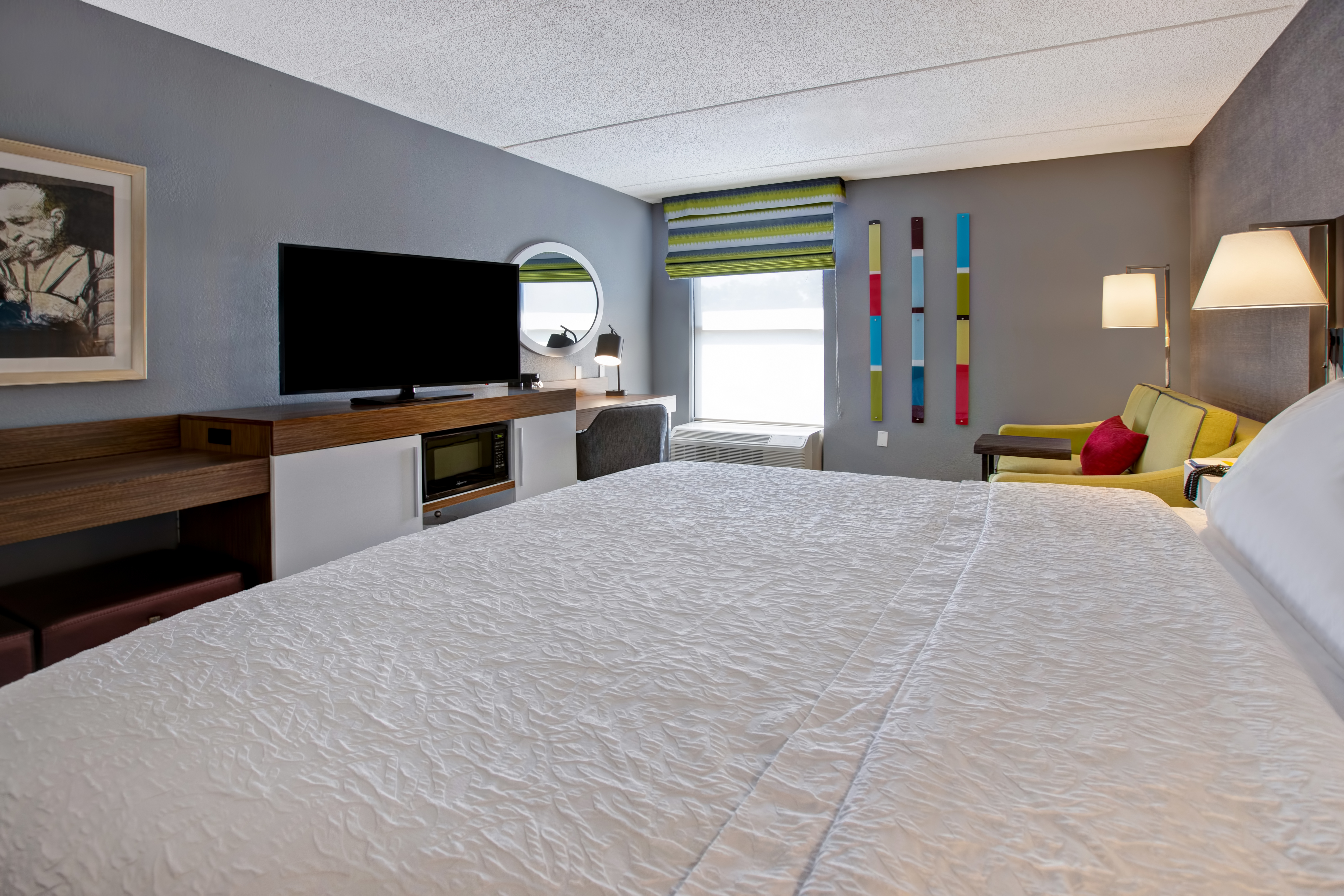 guest room with bed window lounge area and television