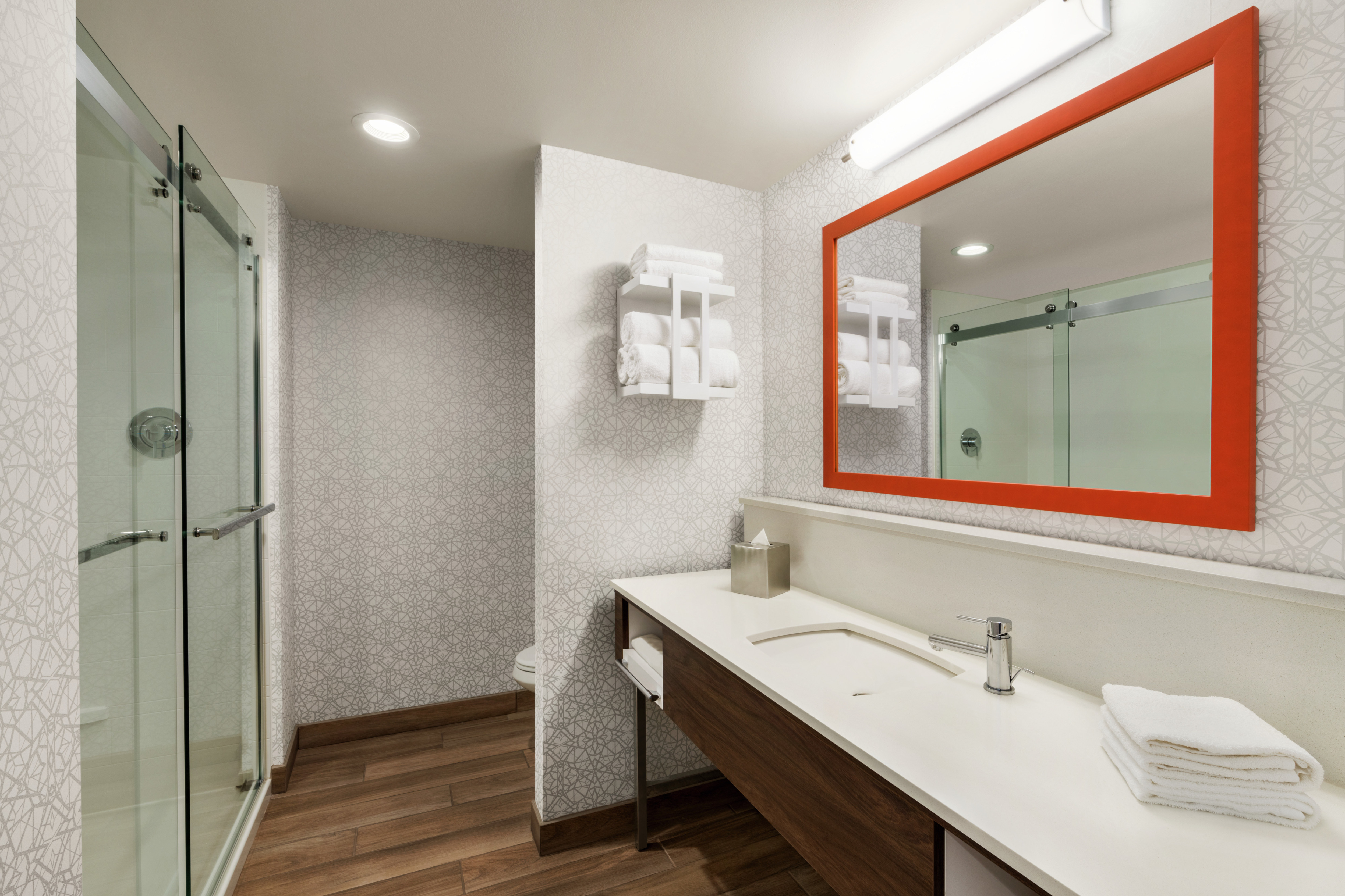 Spacious standard guest bathroom featuring large vanity, mirror, and shower.