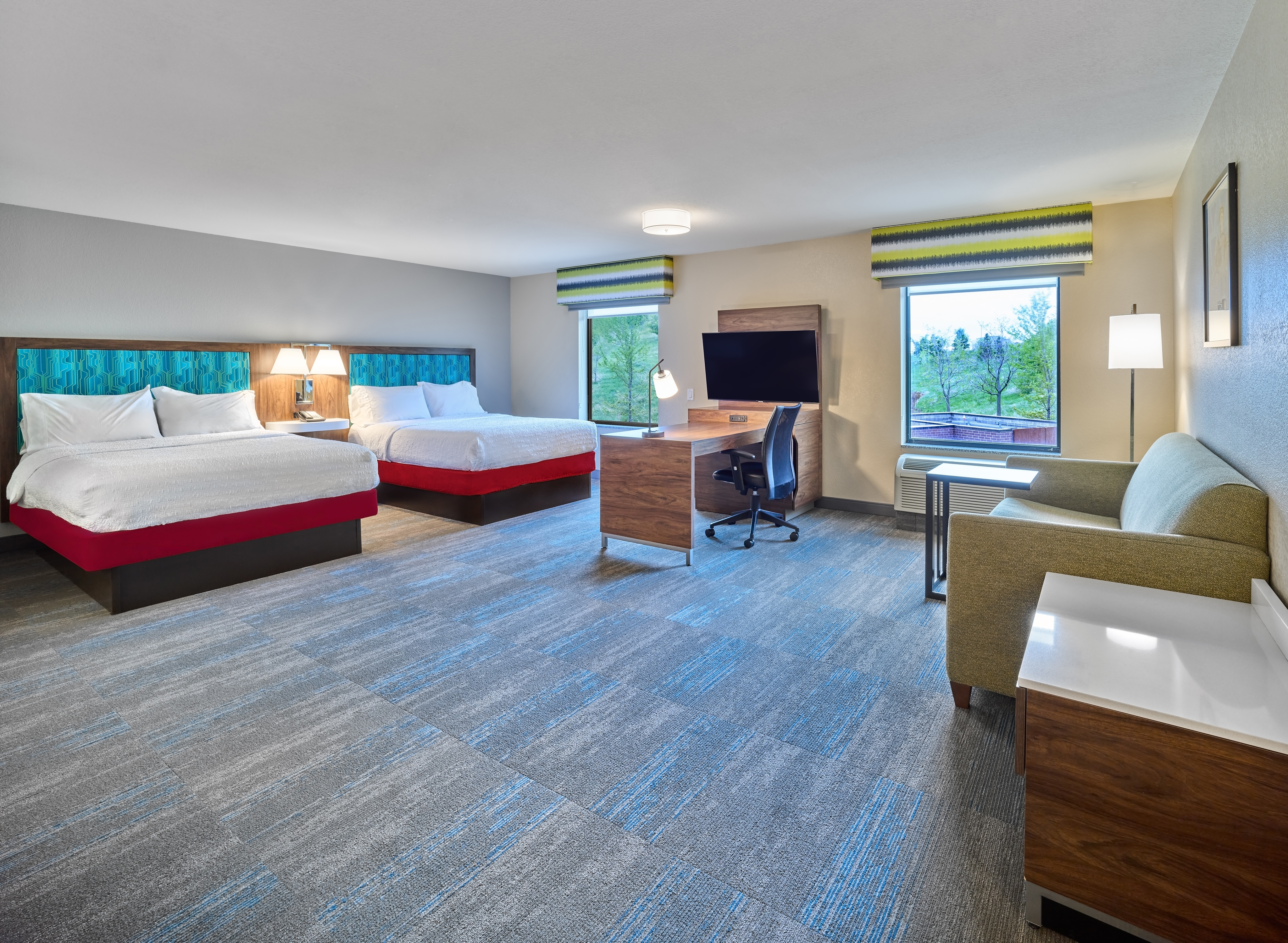 Suite guest room with two beds a lounge area a work desk and a television