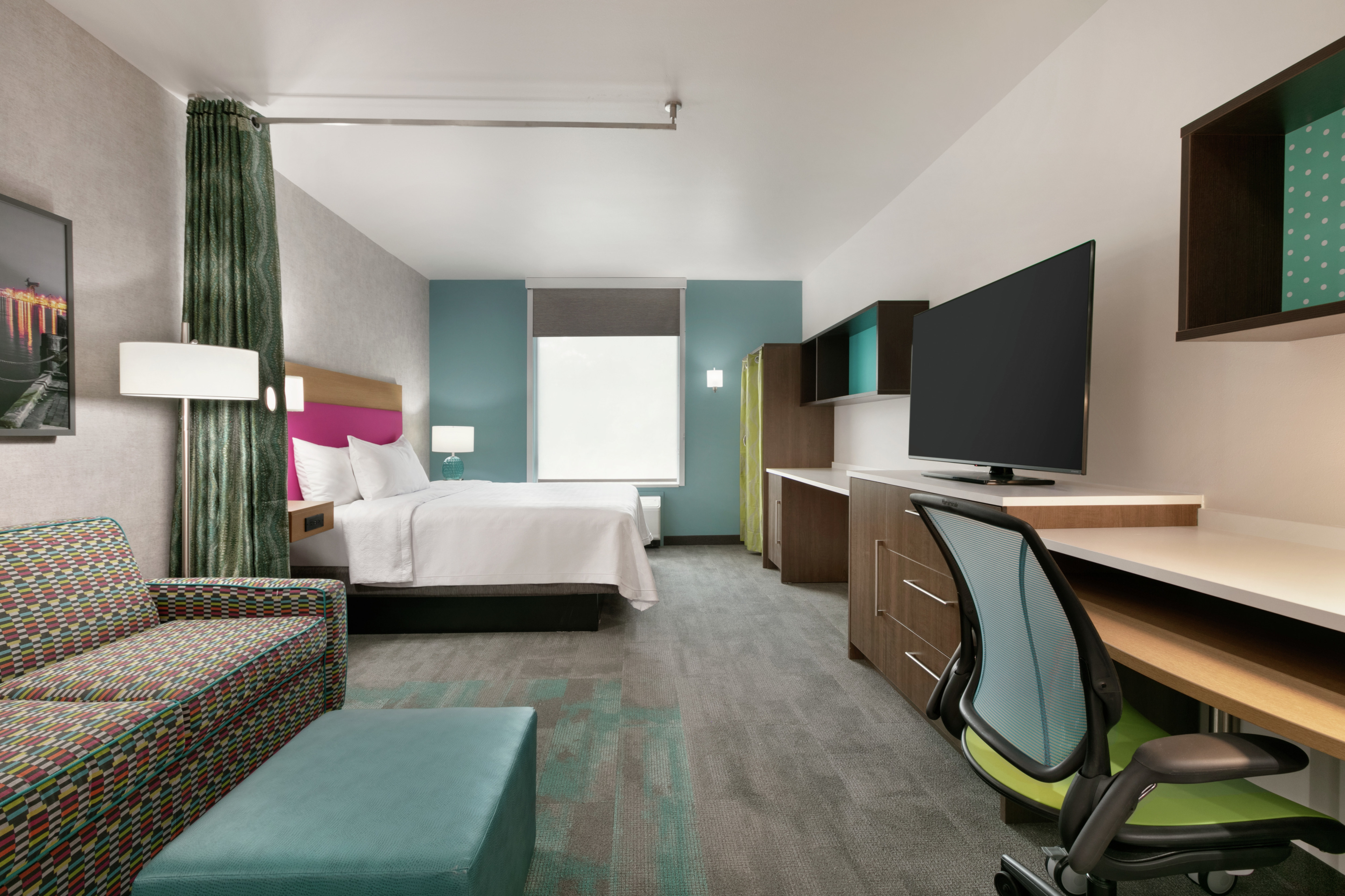 Spacious studio suite featuring sofa, work desk, TV, and comfortable king bed.