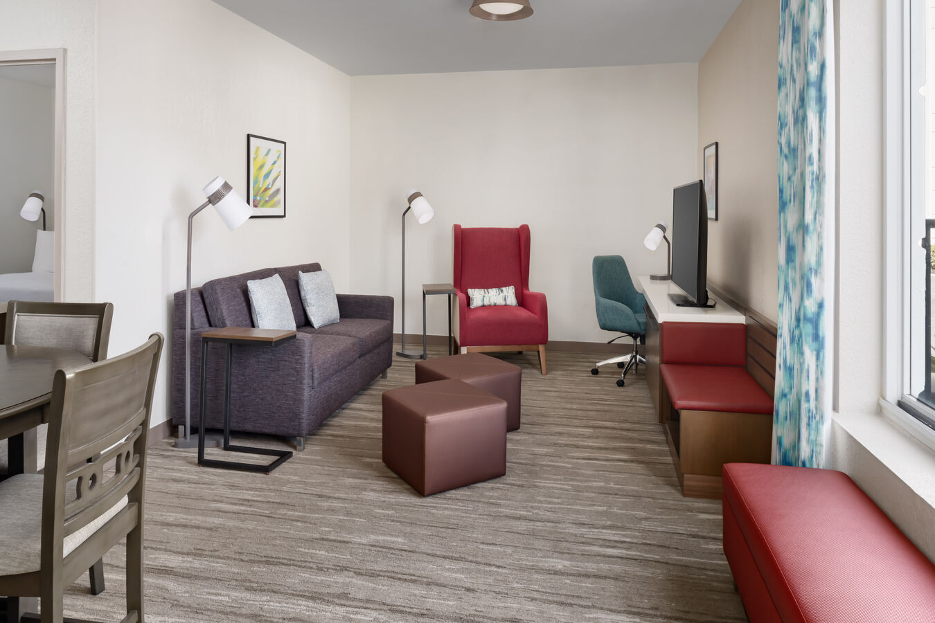 Suite living and lounge area with a sofa, work desk, chairs, and multiple lamps.