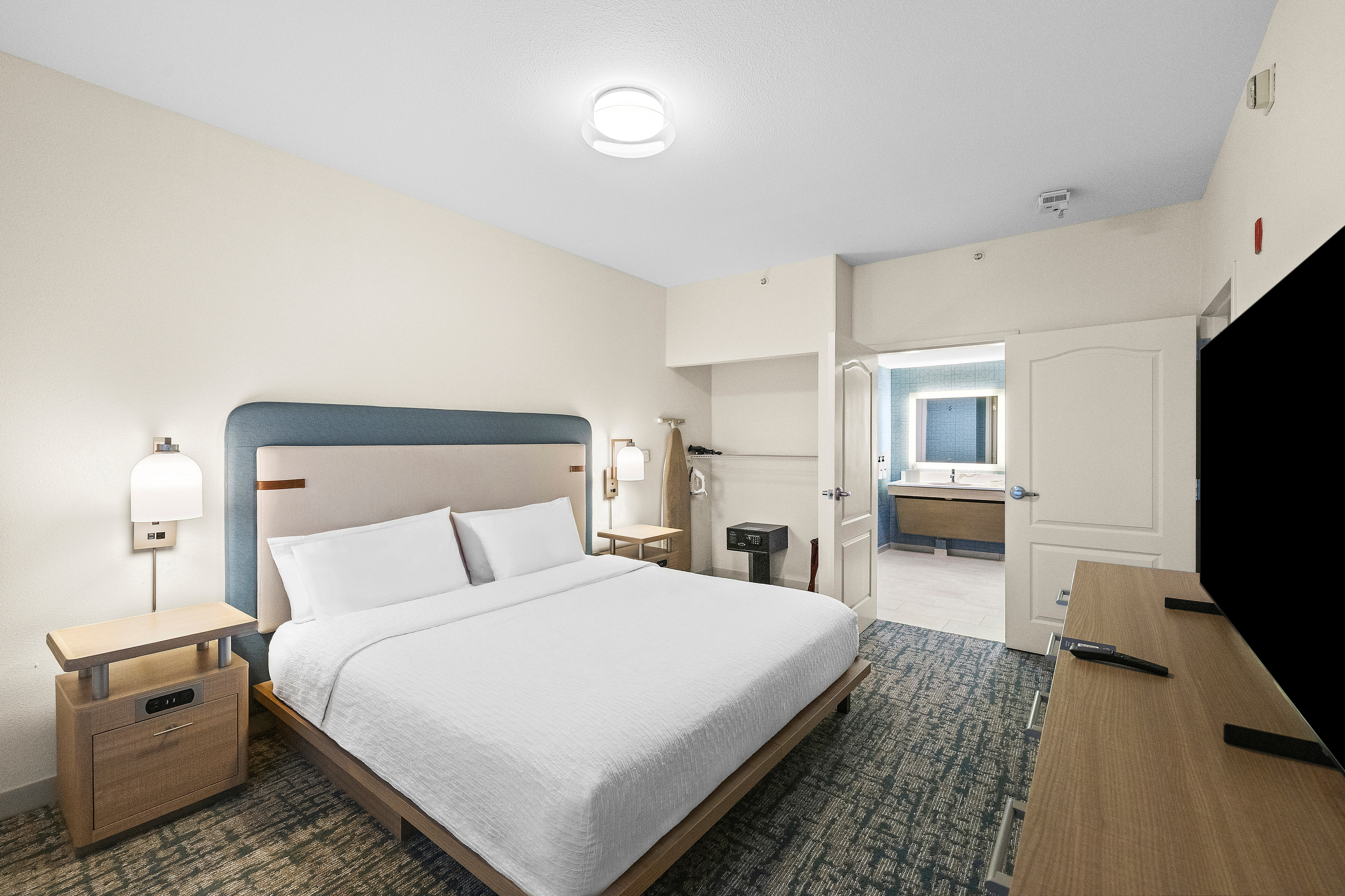 Bed in room with TV, bedside table and lamp