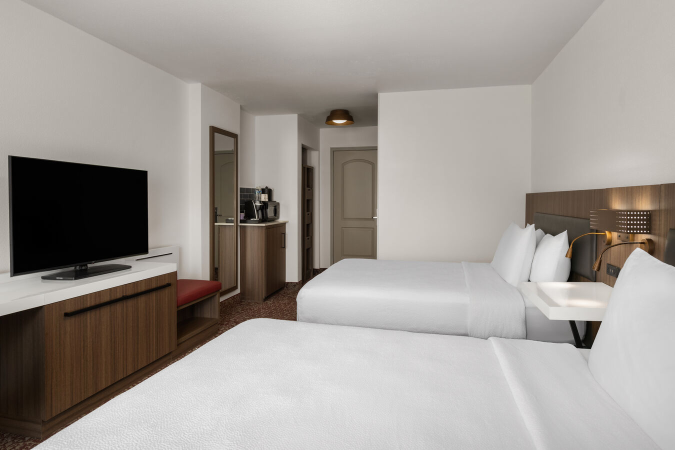 two queen sized beds in front of a television