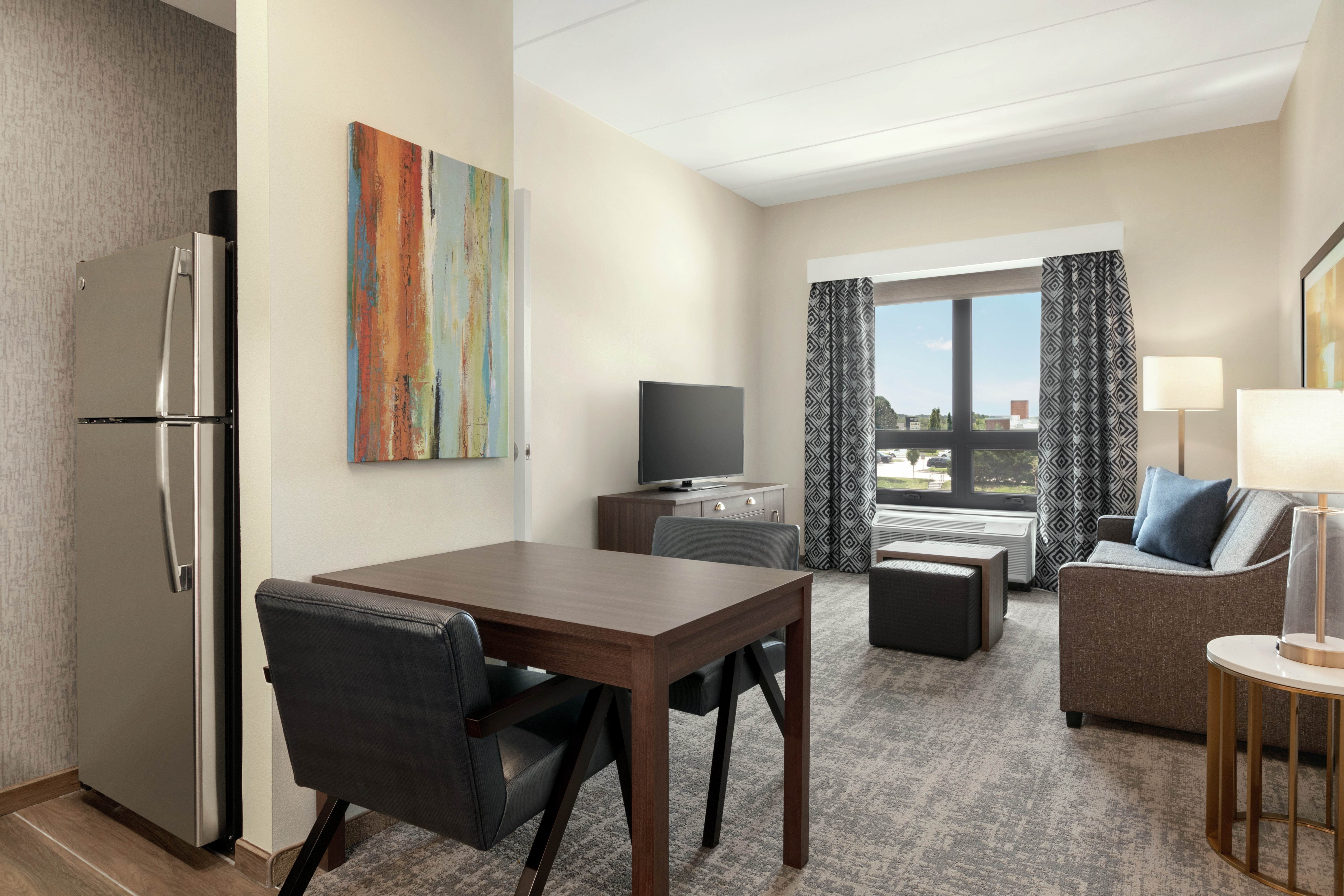 Spacious living area in suite featuring fully equipped kitchen, dining table, sofa, TV, and beautiful outside view.