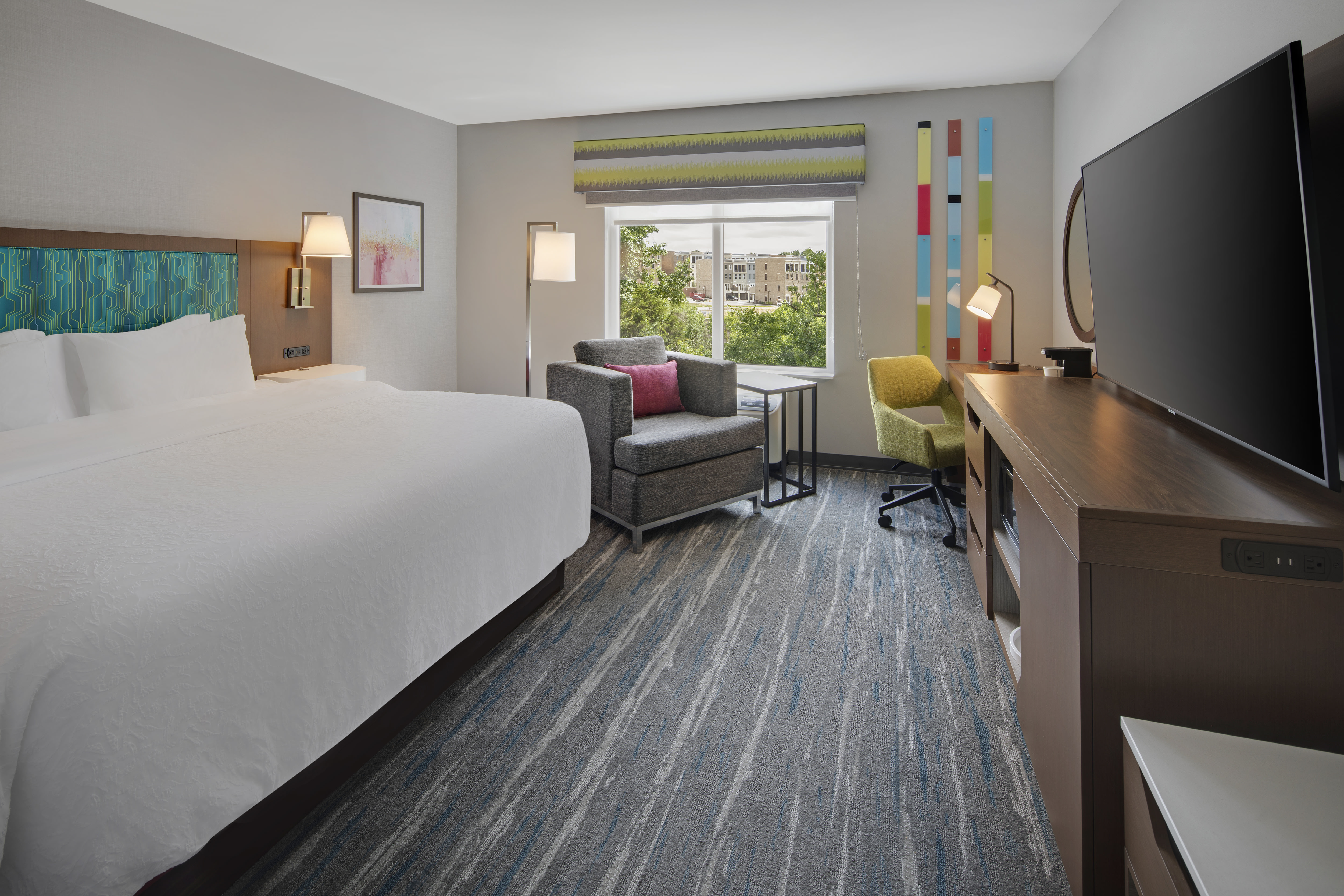Large Bed in Guest Room with Armchair HDTV and Work Desk