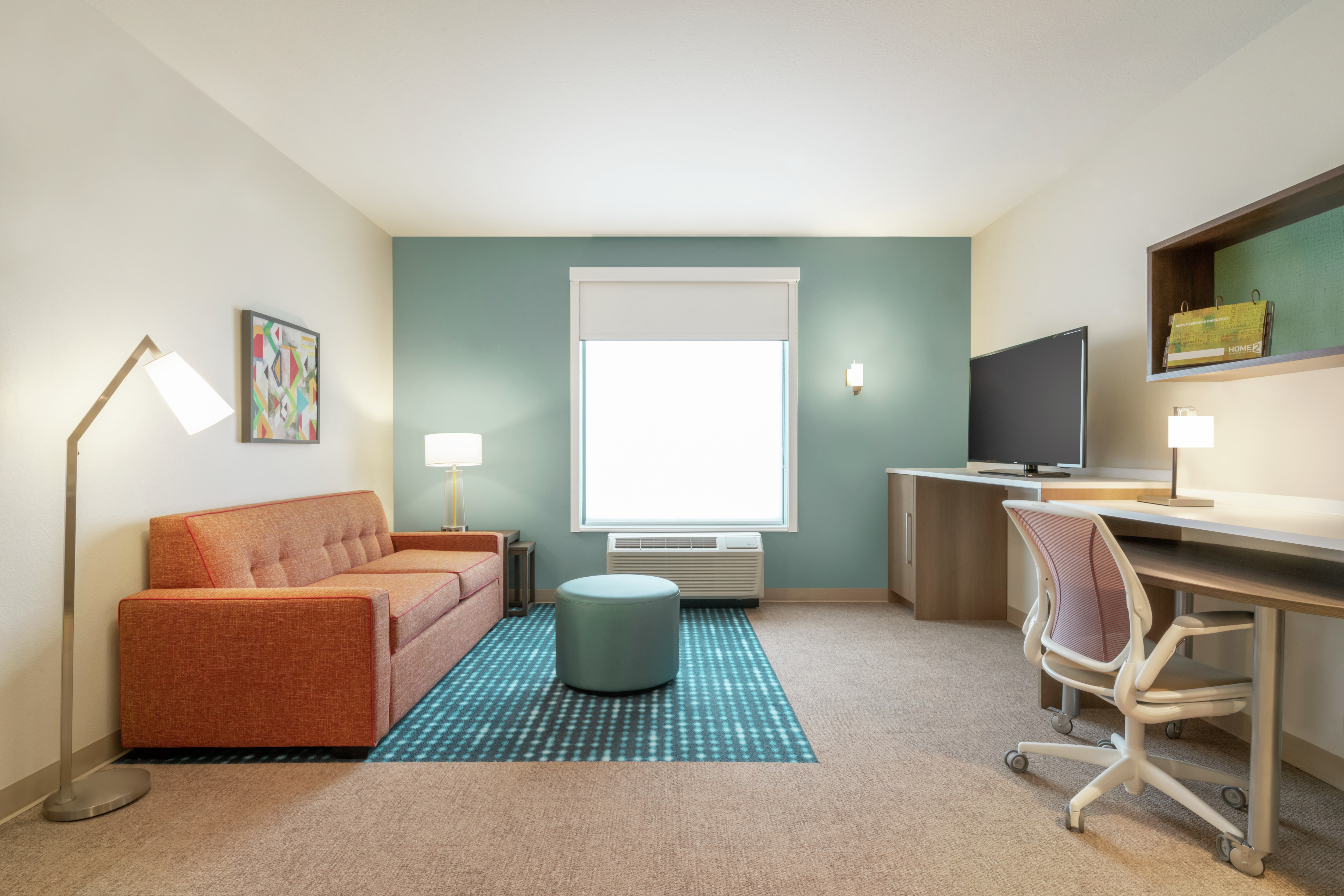 Spacious living area in one bedroom suite featuring comfortable sofa, TV, and work desk.