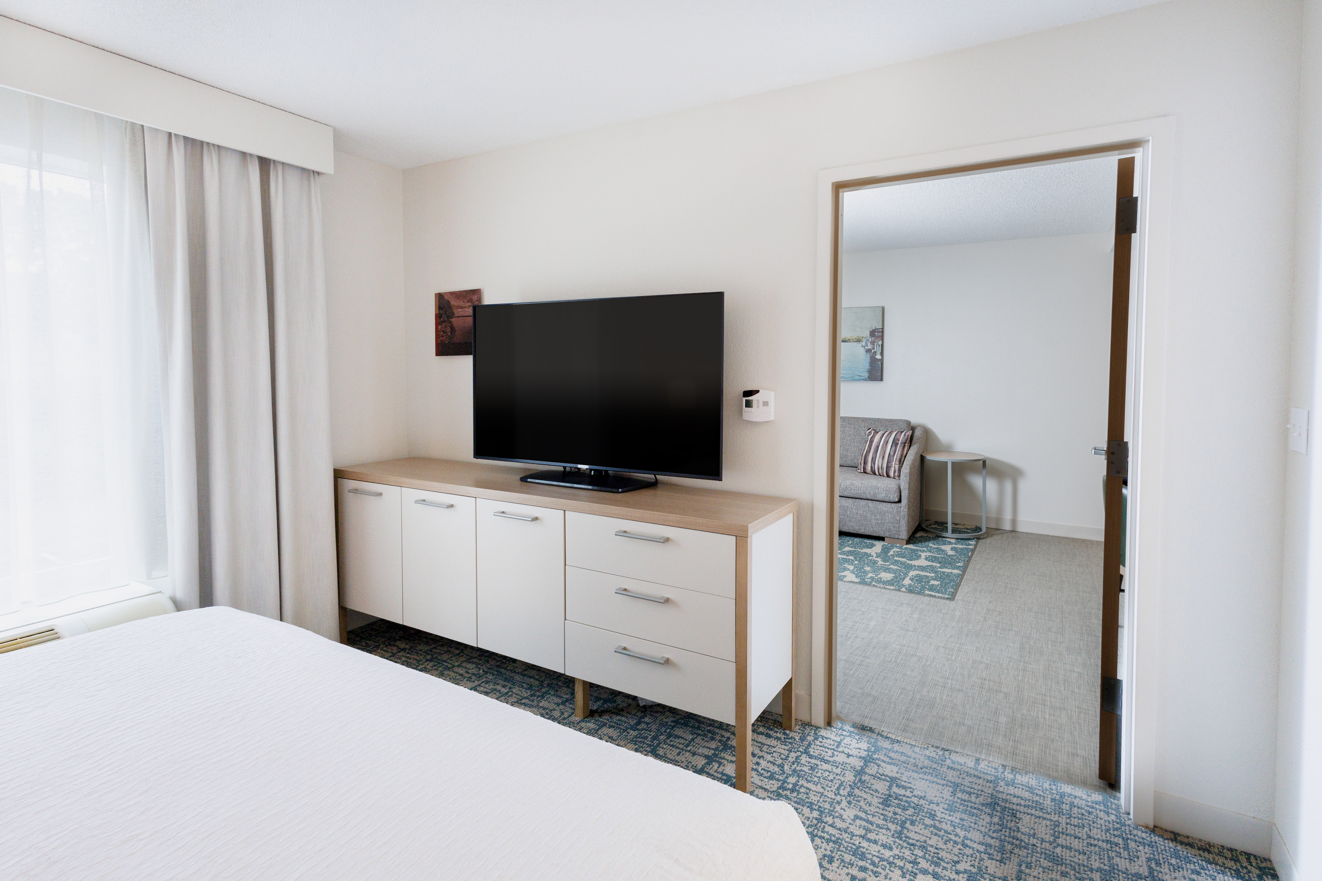 Guest room with TV, bed and view through to lounge area