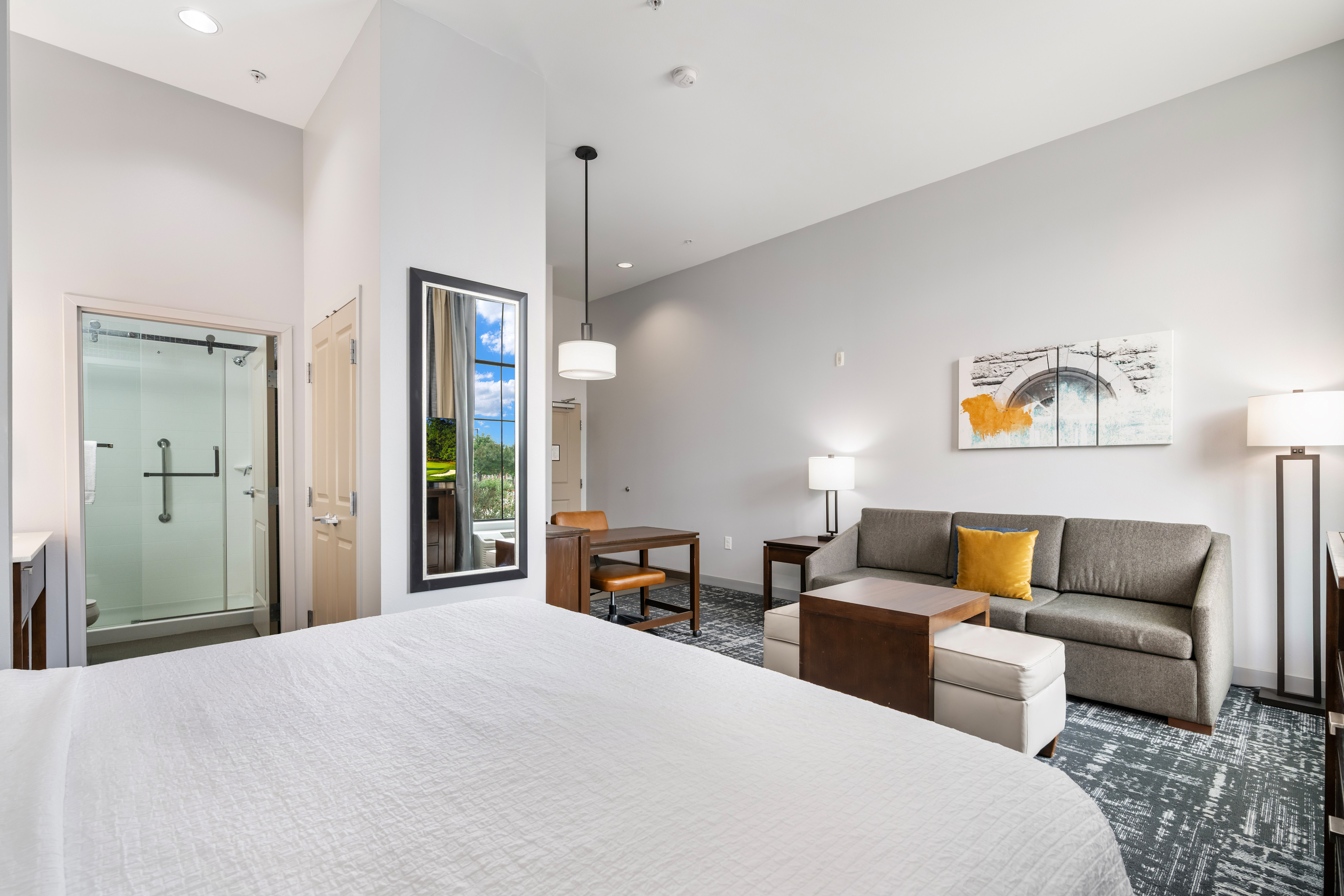 bed with lounge area, work desk and mirror near bathroom