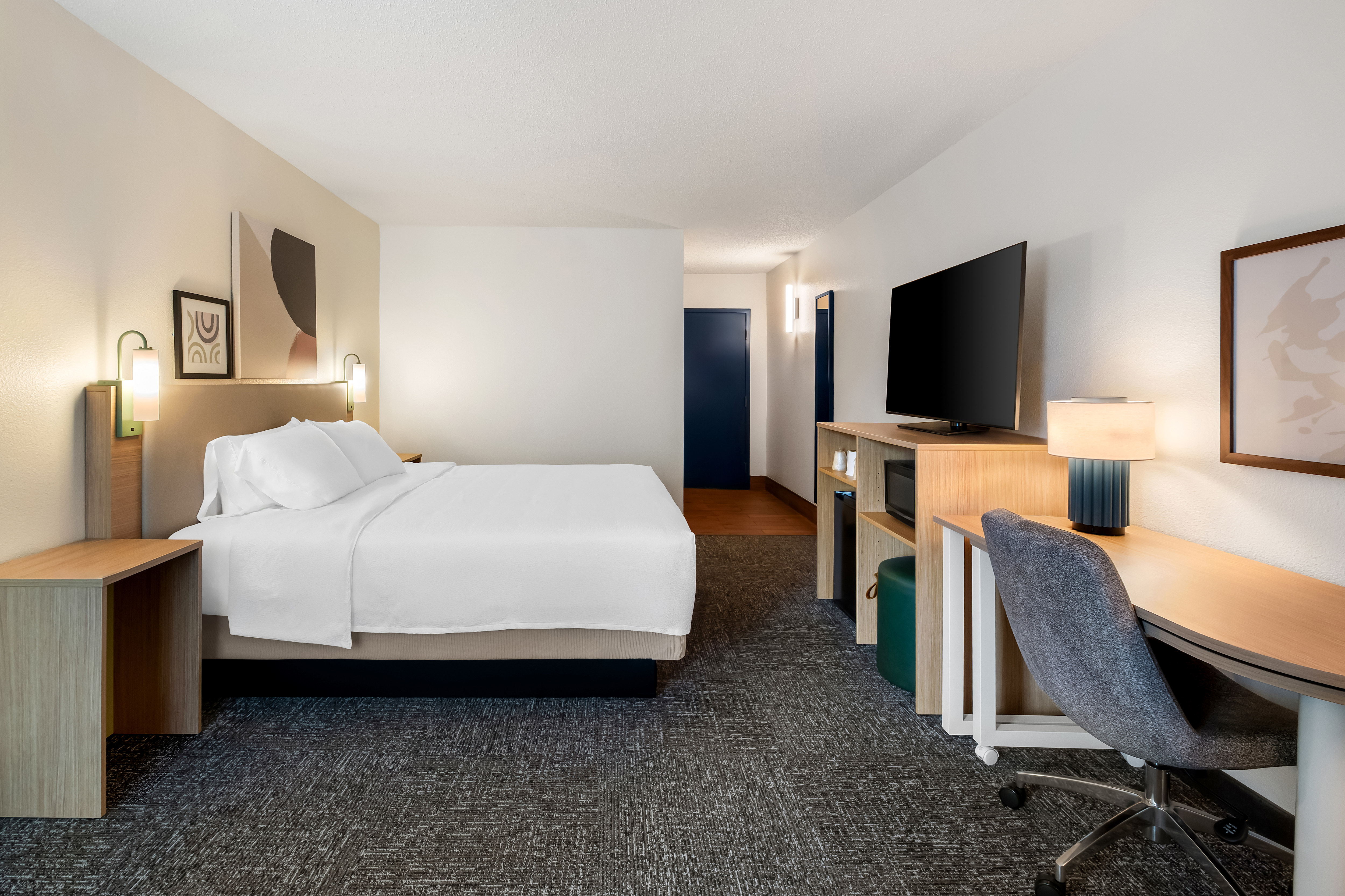 guest bedroom with work desk, chair, and TV