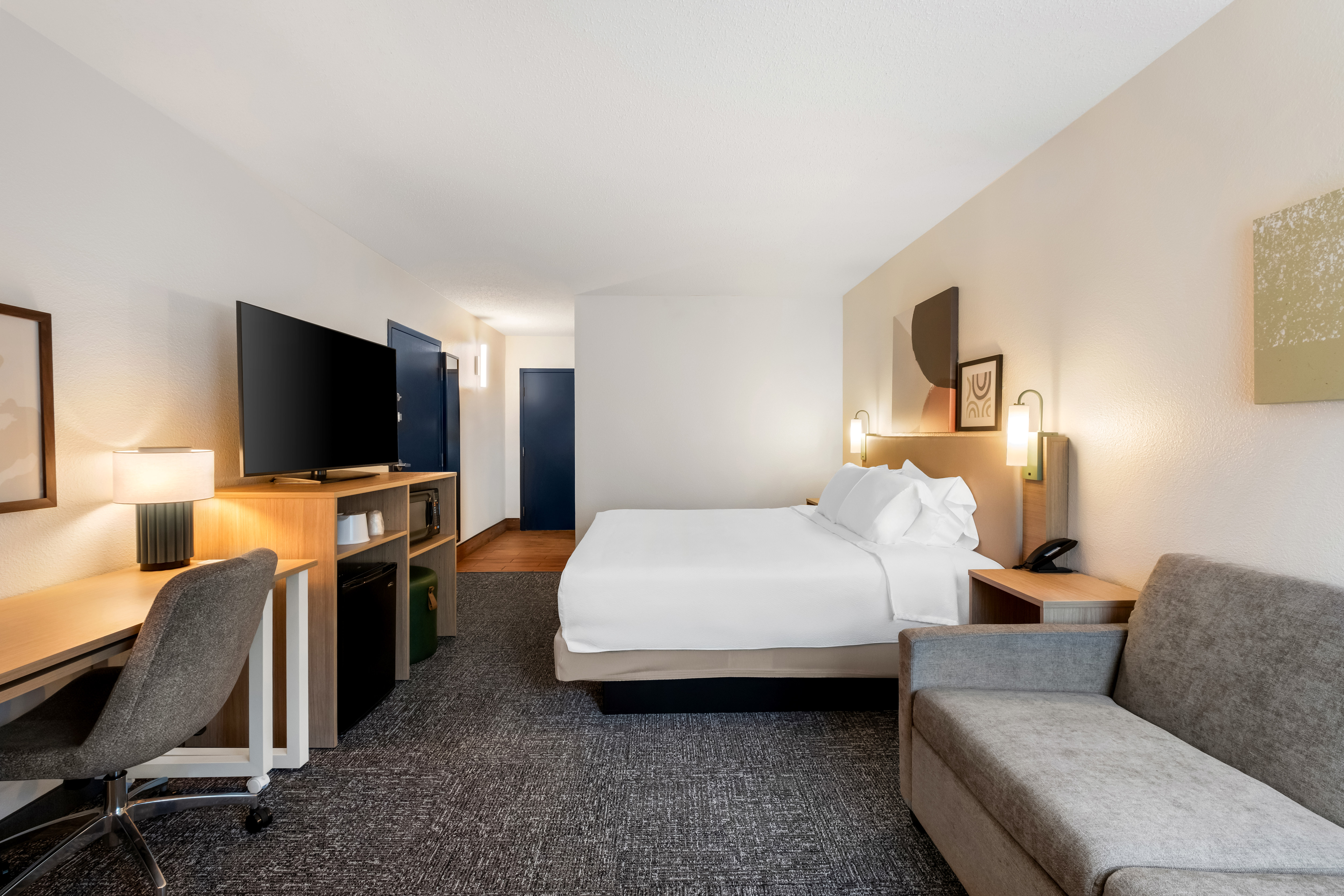 guest bedroom with work desk, chair, and TV