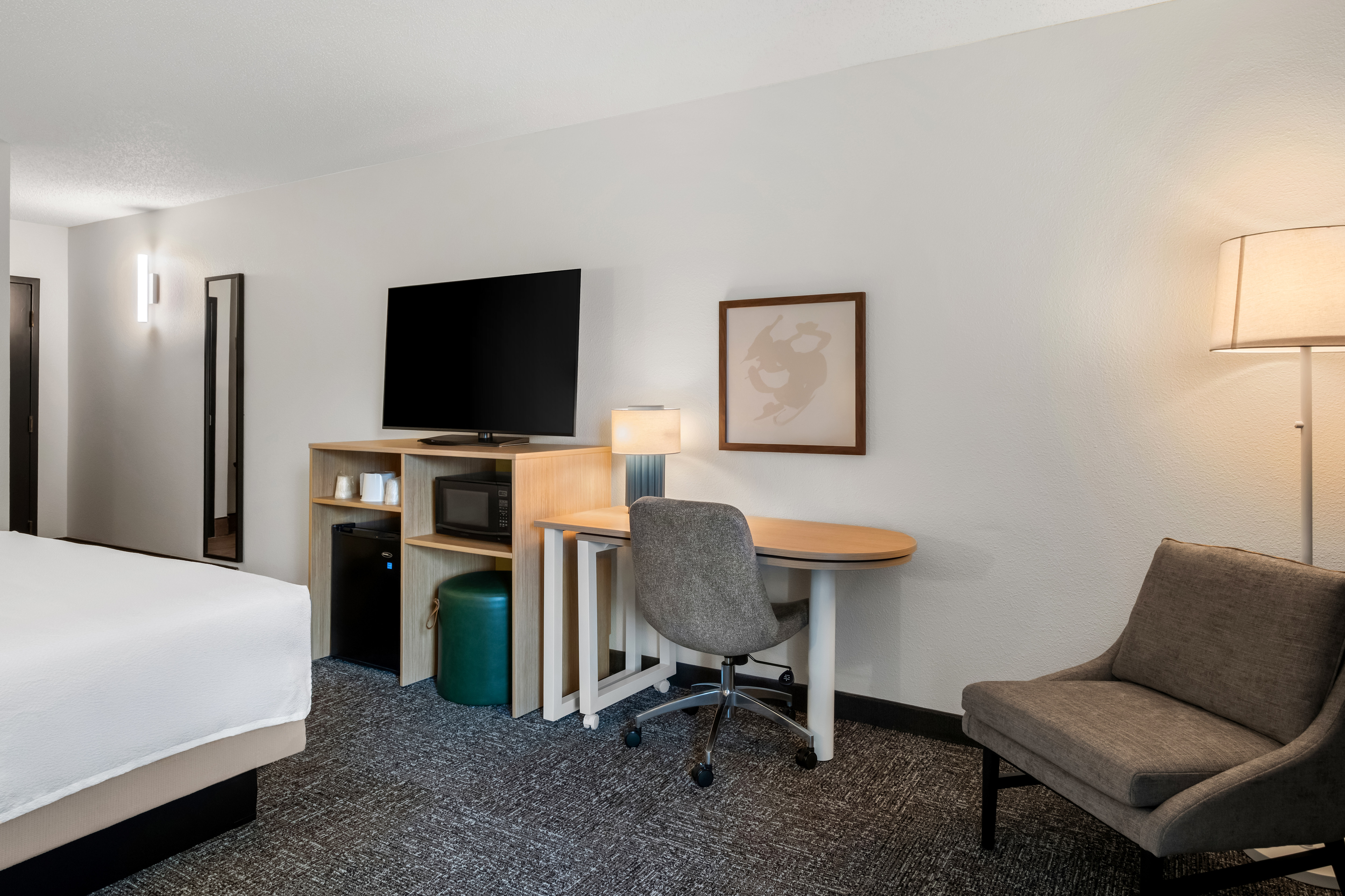 guest bedroom with work desk, chair, and TV